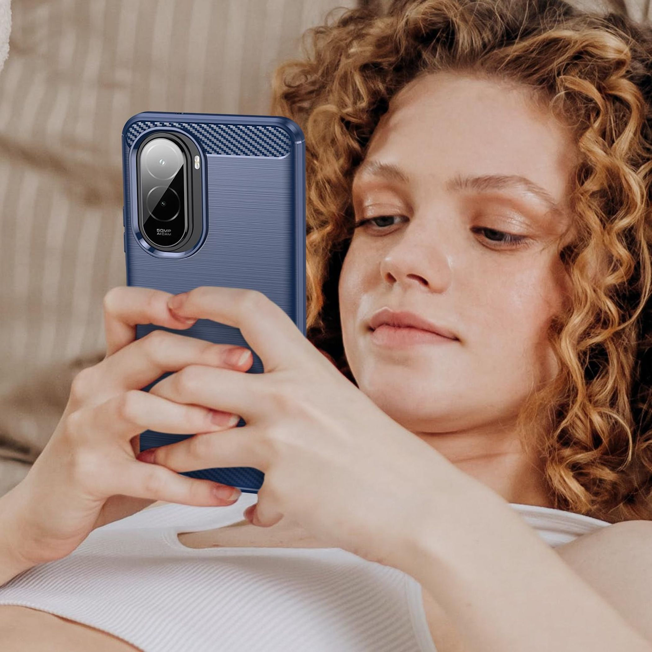 Eine Frau hält ein blaues Telefon. Sie hat lockiges Haar und trägt ein weißes Oberteil. Das Telefon hat eine Kamera.