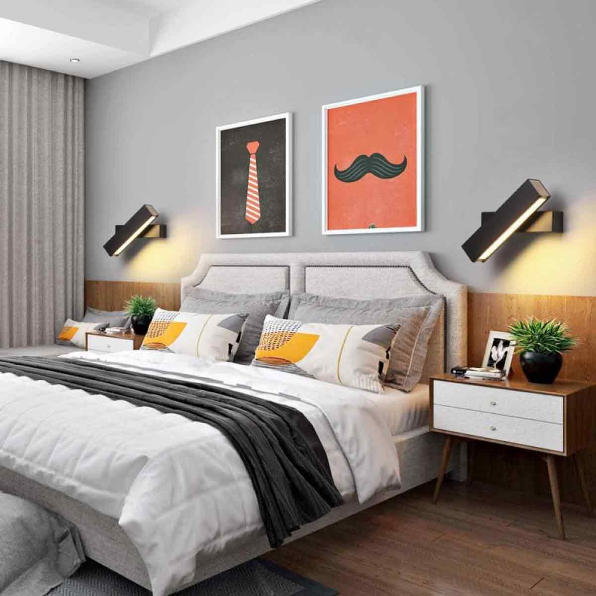 Ein Schlafzimmer mit Bett, zwei Nachttischen, Wandkunst und Wandlampen. Das Bett hat weiße Bettwäsche mit einer grauen Decke.