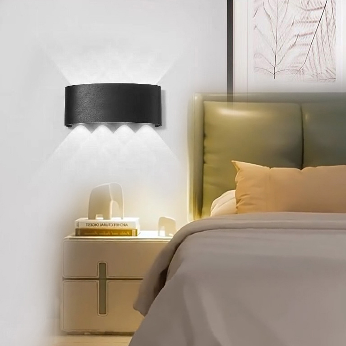 Ein modernes Schlafzimmer mit einer schwarzen Wandleuchte, einem Nachttisch mit Büchern und einem Bett mit Kissen.