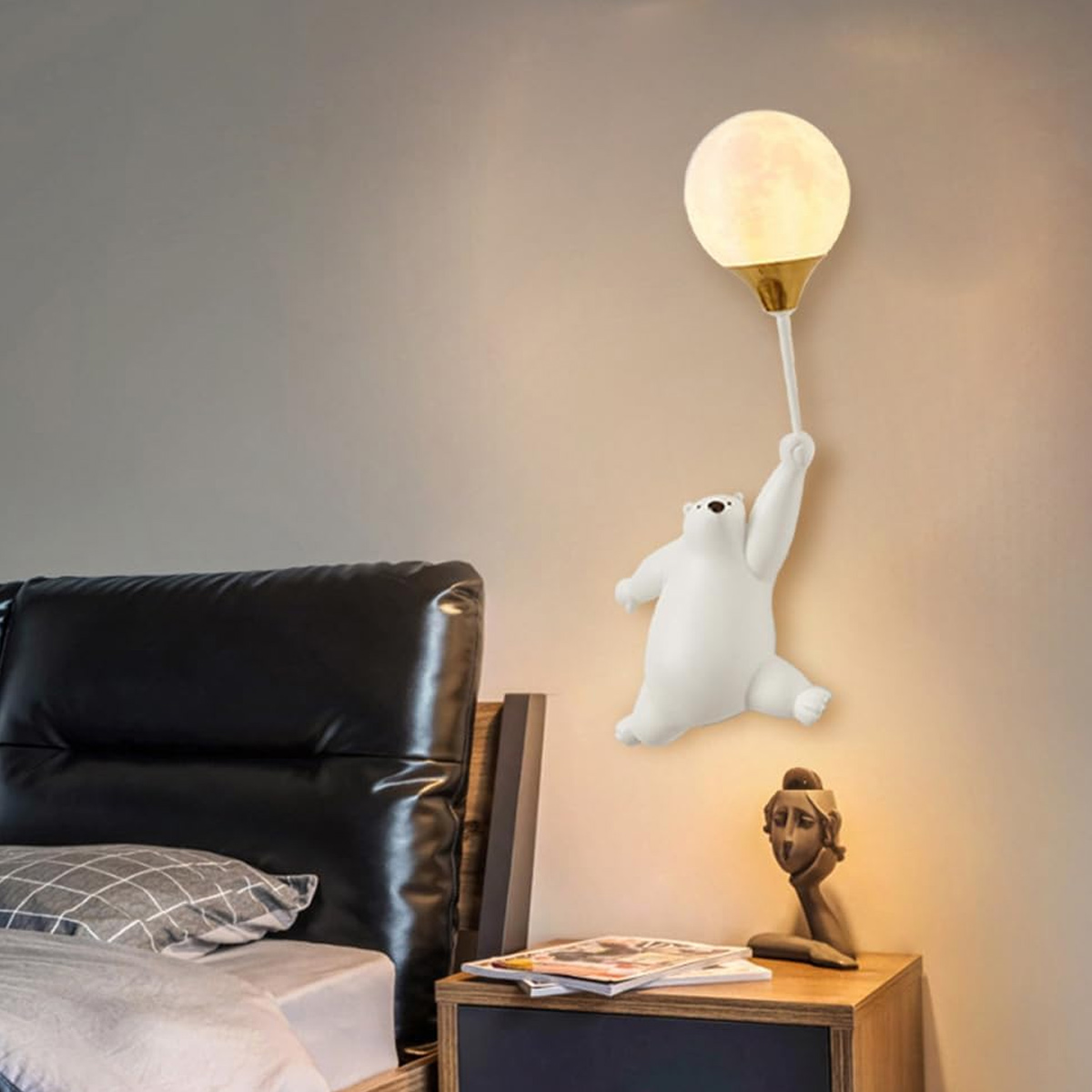 Eine weiße Bärenlampe hält eine Ballonlampe. Ein Bett und ein Nachttisch befinden sich im Vordergrund, mit einer Skulptur auf dem Nachttisch.