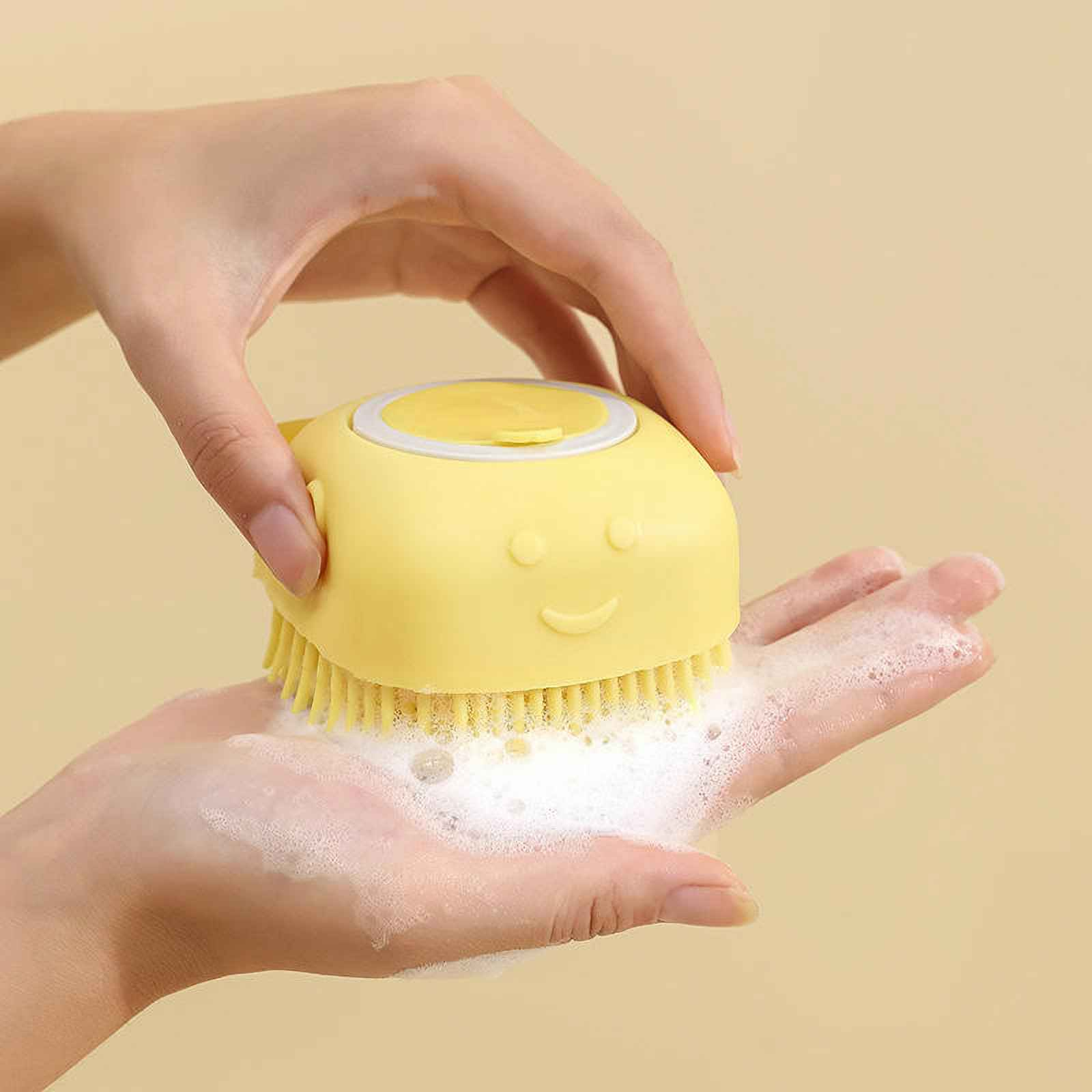 Eine gelbe Baby-Badbürste mit Smiley-Gesicht in einer Hand mit Seife.
