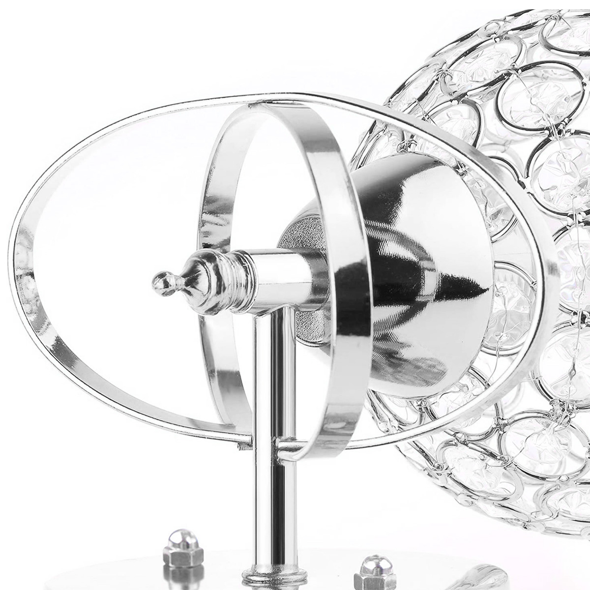 Nahaufnahme einer silbernen Lampe. Sie hat rechts eine Kristallkugel, Metallringe und einen Ständer. Der Hintergrund ist weiß.