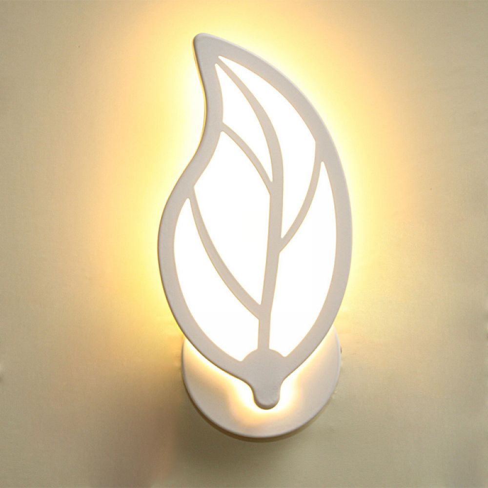 Eine weiße, blattförmige Wandleuchte ist an einer beigefarbenen Wand befestigt. Die Lampe leuchtet und strahlt ein warmes Licht aus.
