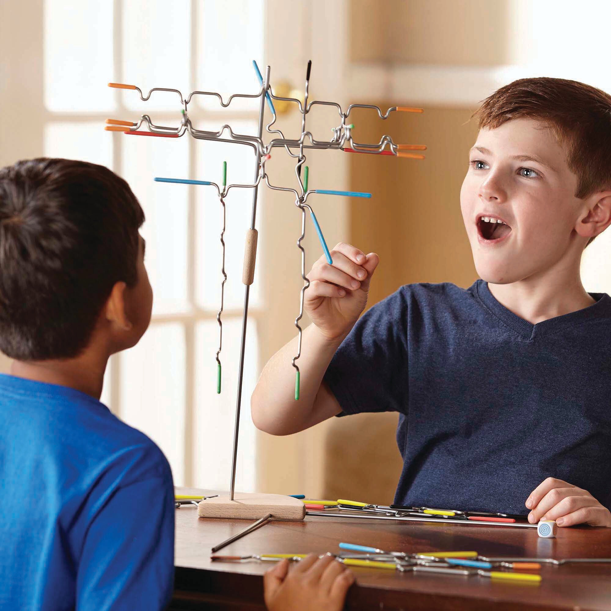 Zwei Jungen spielen mit einem Balance-Spielzeug. Ein Junge ist aufgeregt. Das Spielzeug hat farbige Stäbe auf einem Holzsockel.