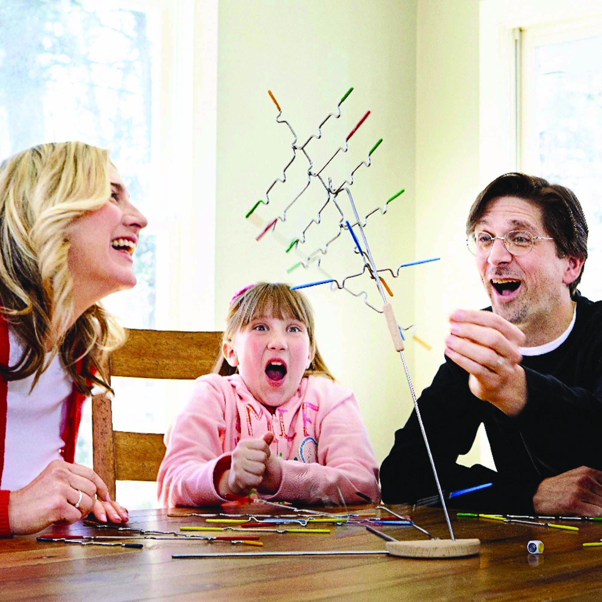 Familie spielt ein Balance-Spiel. Das Spiel hat farbige Stäbe. Die Leute lächeln und reagieren auf das Spiel.