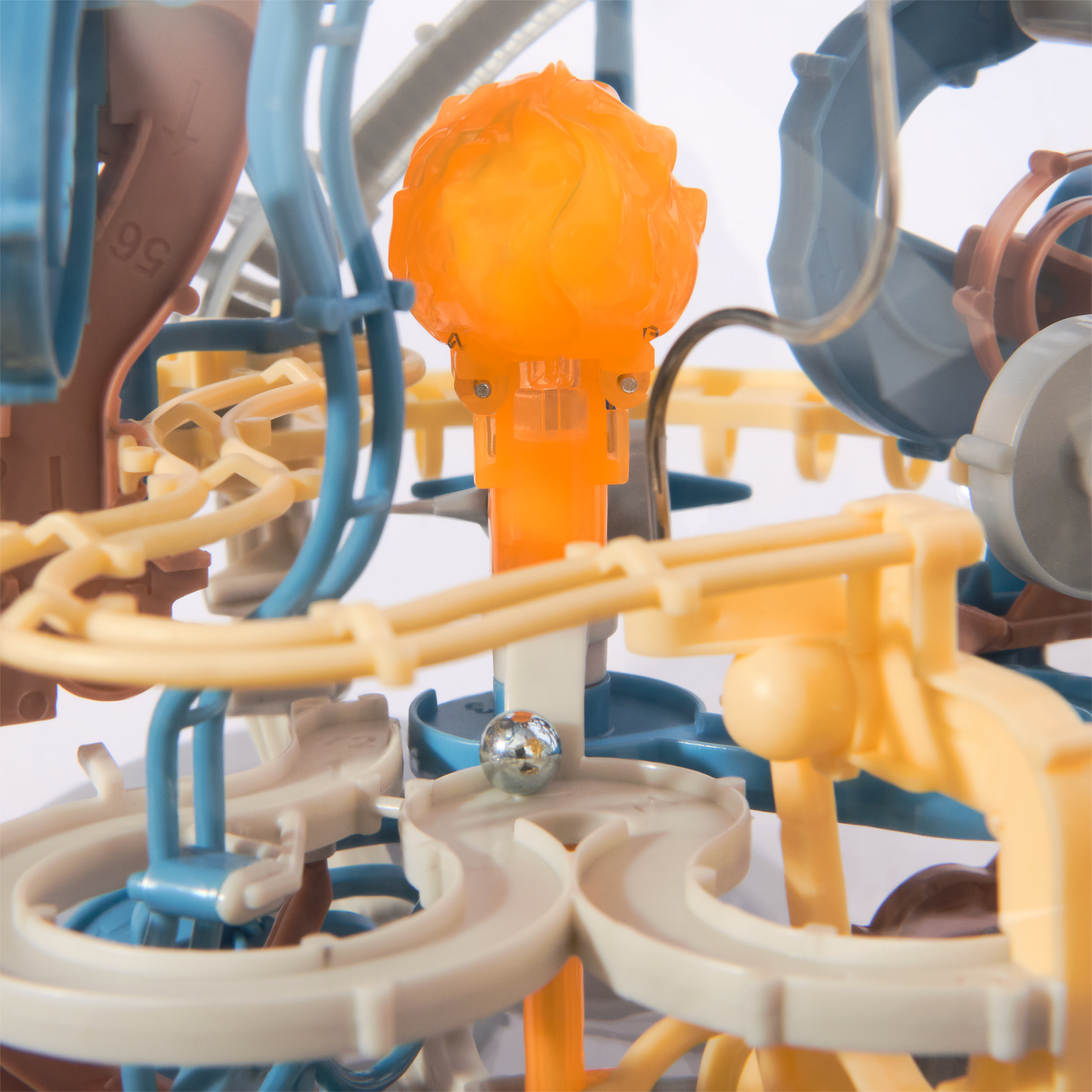 Złożona zabawka labiryntu kulkowego w różnych kolorach. Srebrna kulka jest na torze. Pomarańczowe, niebieskie i żółte elementy plastikowe.