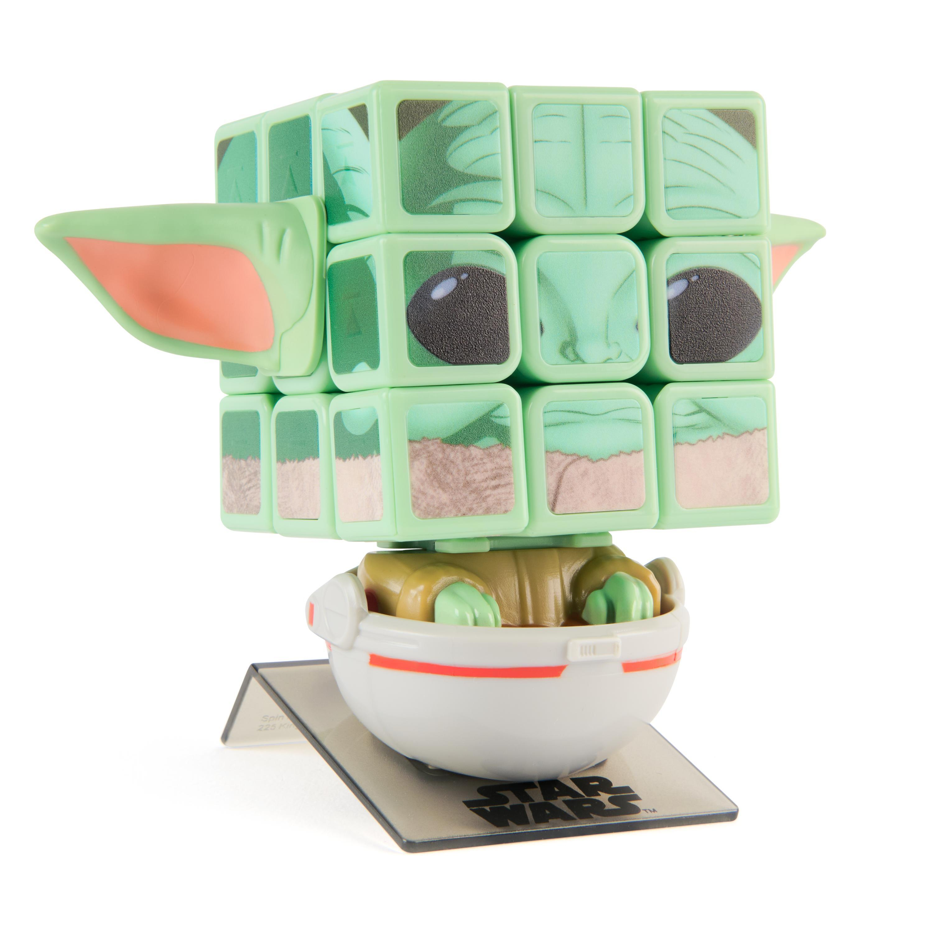 Ein Baby-Yoda-Rubik's Cube steht auf einem Ständer. Der Würfel bildet den Kopf. Die Figur befindet sich in einer weißen Kapsel.