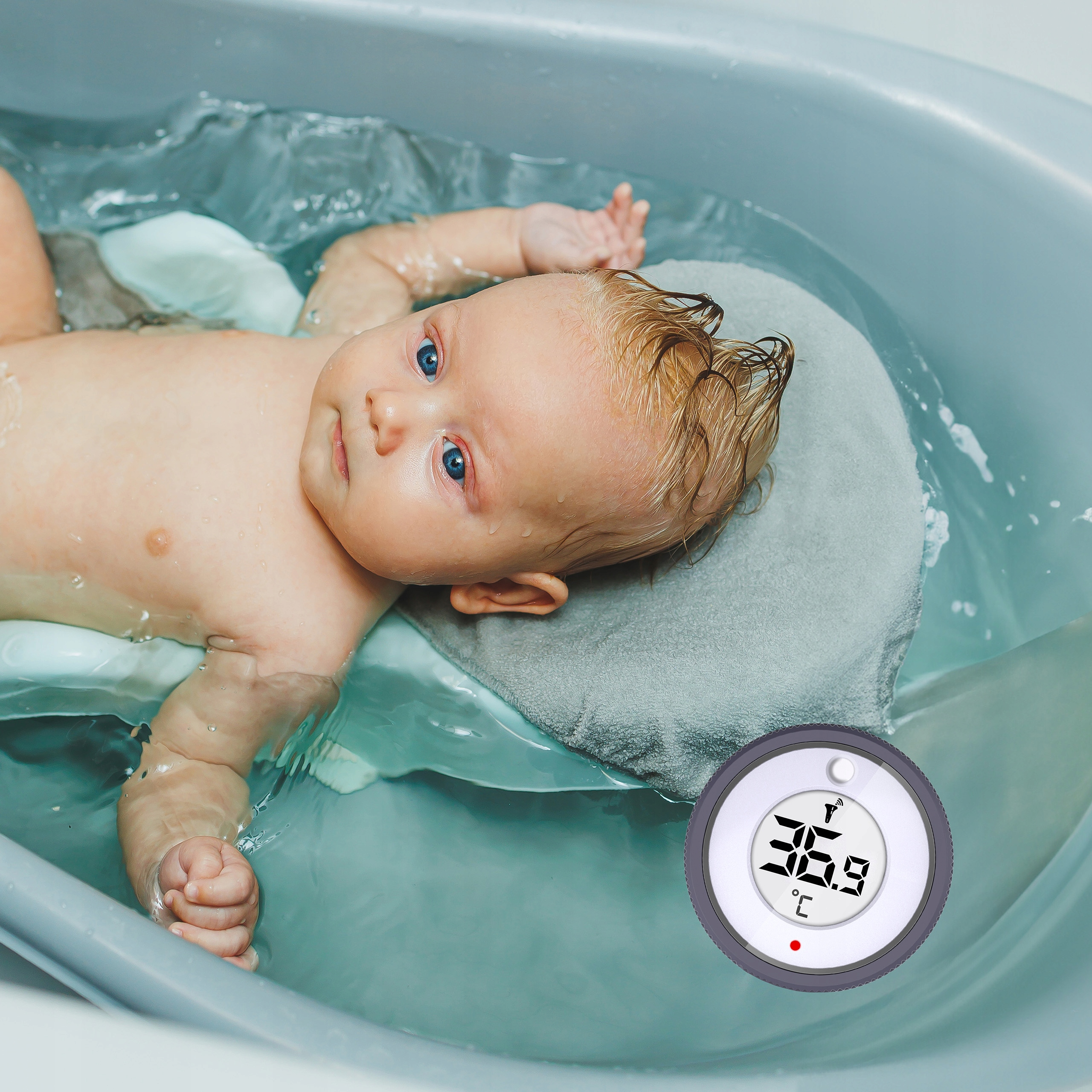 Dziecko w kąpieli. Woda i termometr pokazują 36,9 stopni. Dziecko ma niebieskie oczy.