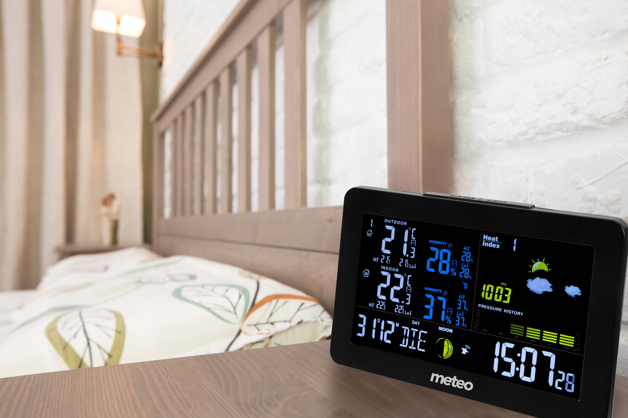 Cyfrowa stacja pogodowa wyświetla temperaturę zewnętrzną i wewnętrzną, wilgotność i czas na drewnianym stole.