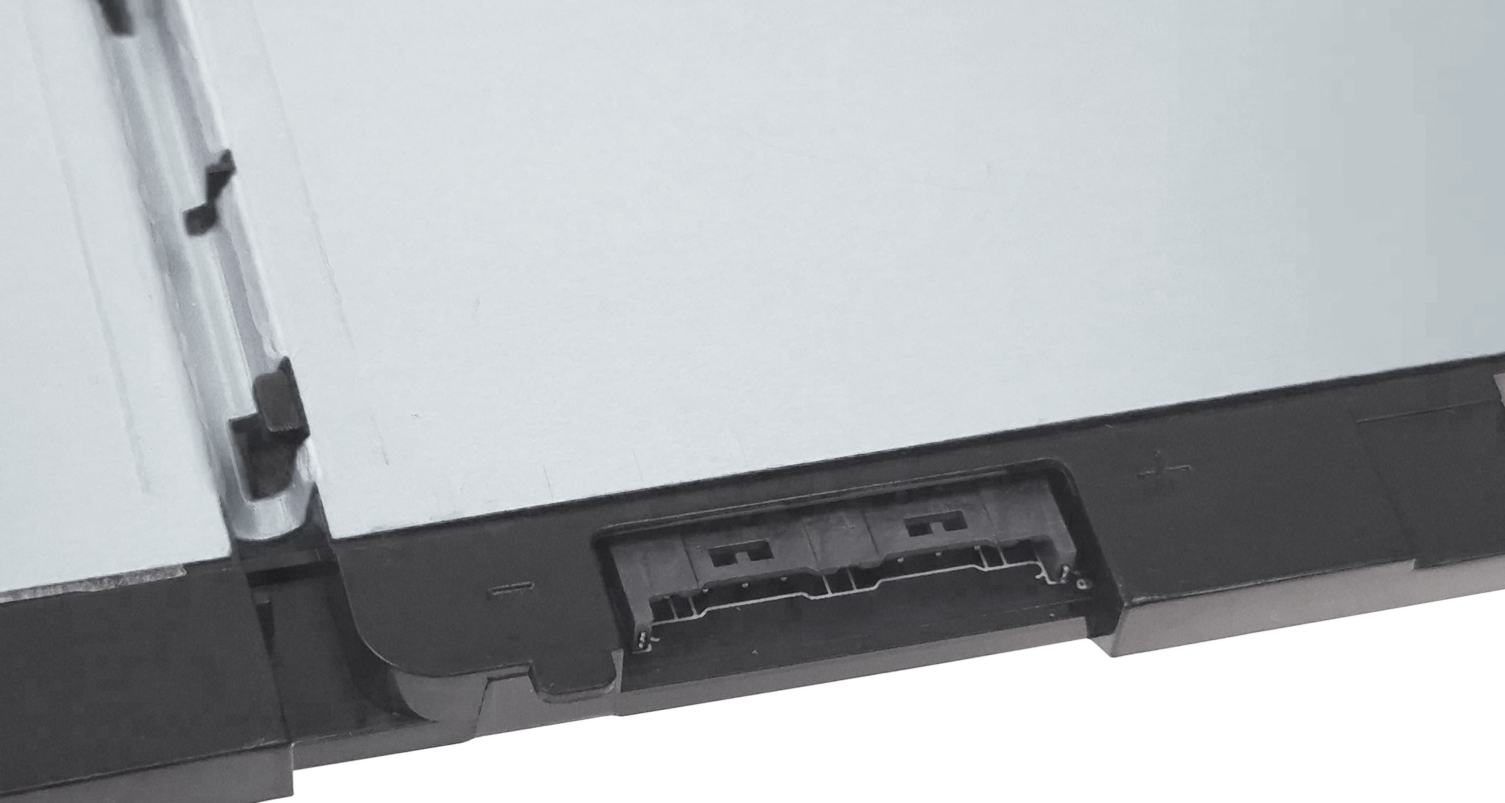 Zbliżenie czarnego złącza na srebrnej powierzchni. Złącze ma wiele pinów i jest otoczone czarną plastikową ramką.