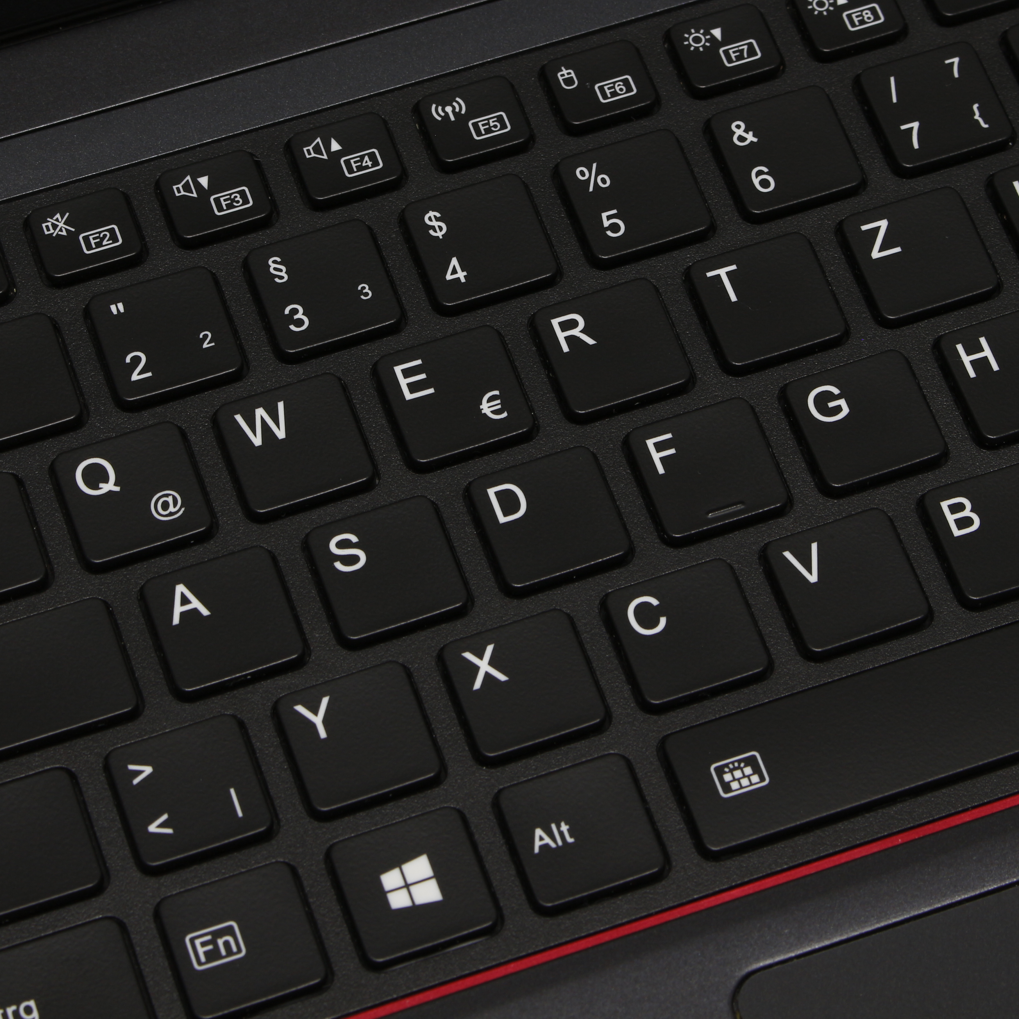 Primer plano de un teclado de portátil negro, las letras y símbolos son blancos. Línea roja en la base.