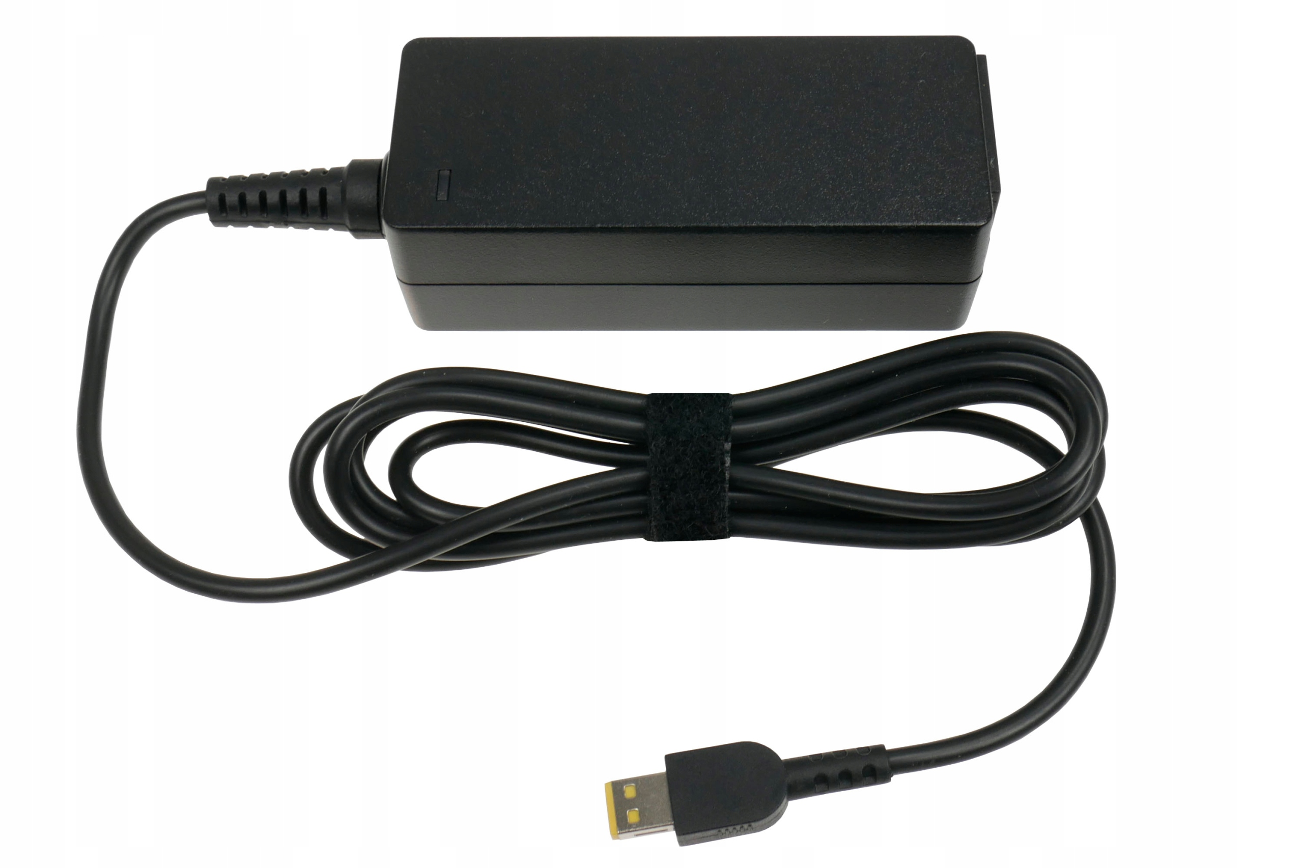 Czarna ładowarka do laptopa z czarnym kablem. Kabel jest owinięty rzepem. Tło jest białe.