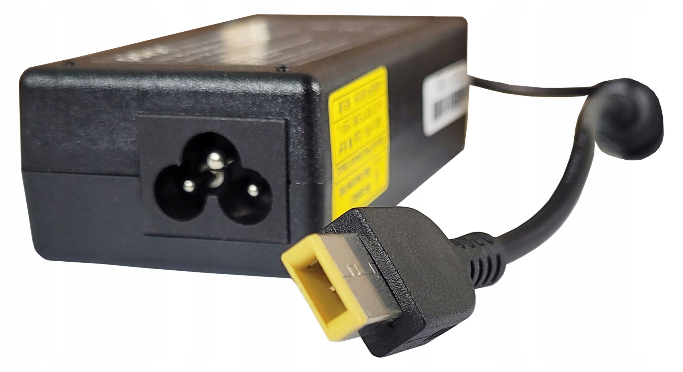 Czarna ładowarka do laptopa z czarnym kablem i żółtym złączem, na białym tle.