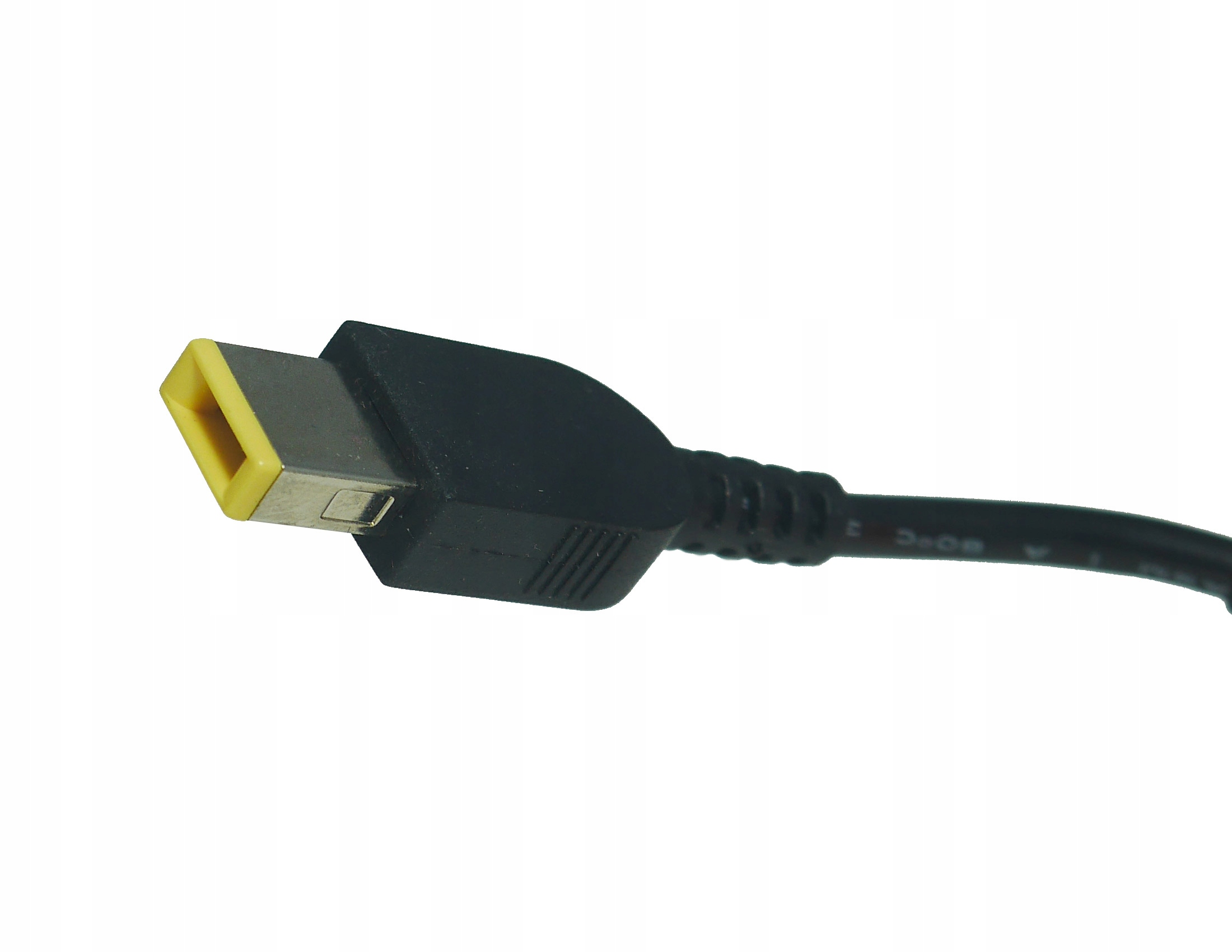 Zbliżenie czarnego kabla ładowarki do laptopa z żółtym i metalowym złączem na białym tle.