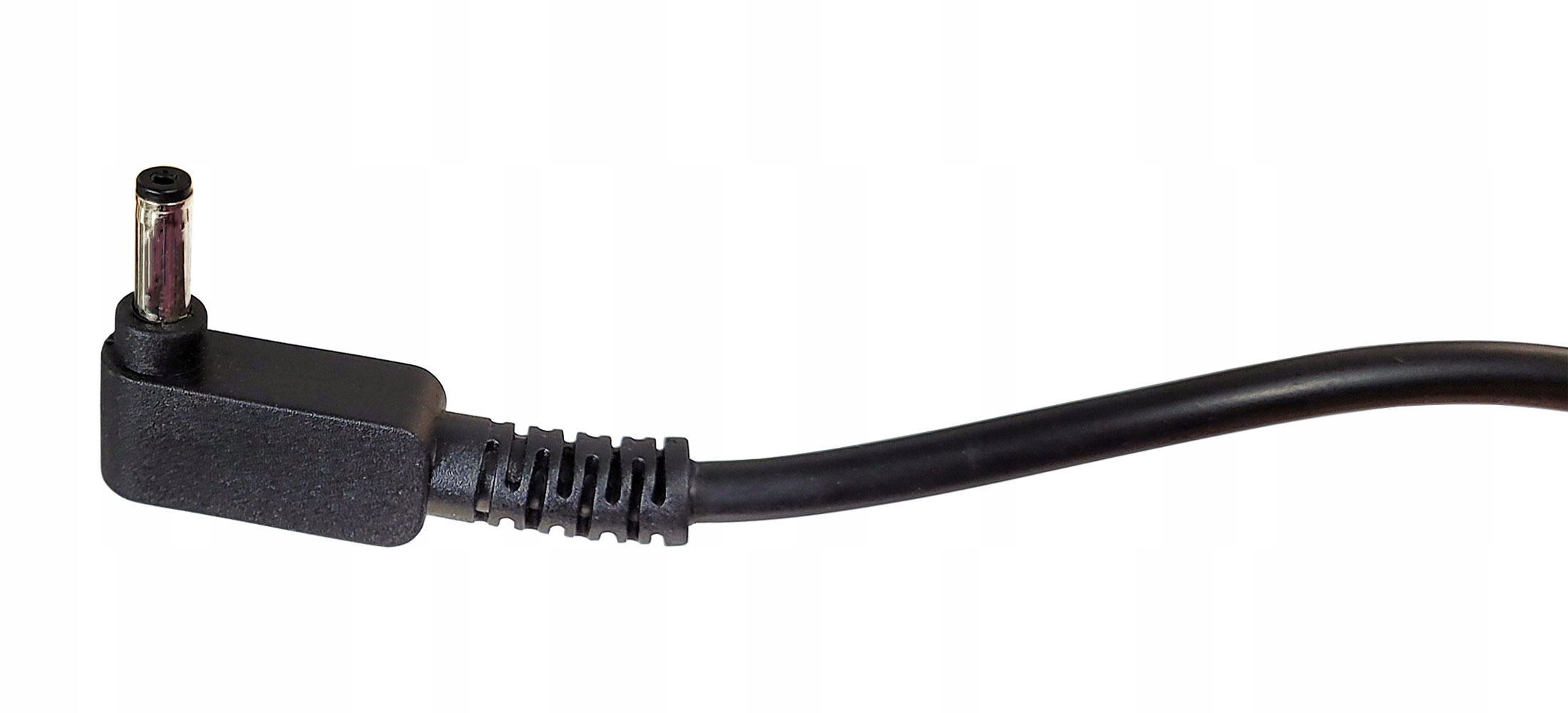 Zbliżenie czarnego kabla zasilającego ze srebrną końcówką, pod kątem 90 stopni. Tło jest białe.