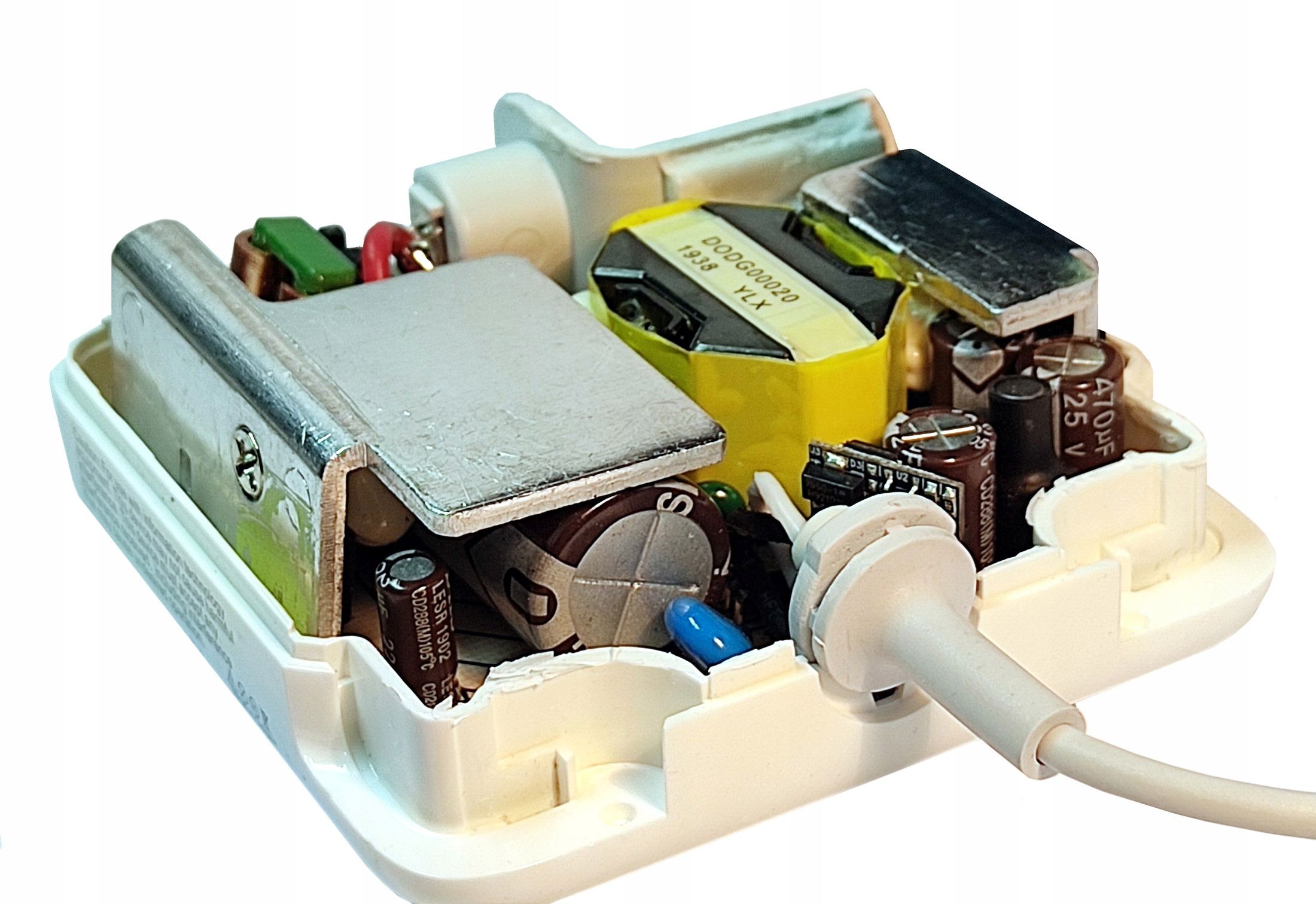 Otwarty zasilacz z elementami elektronicznymi: kondensatory, transformator i przewody. Biały kabel wystaje.