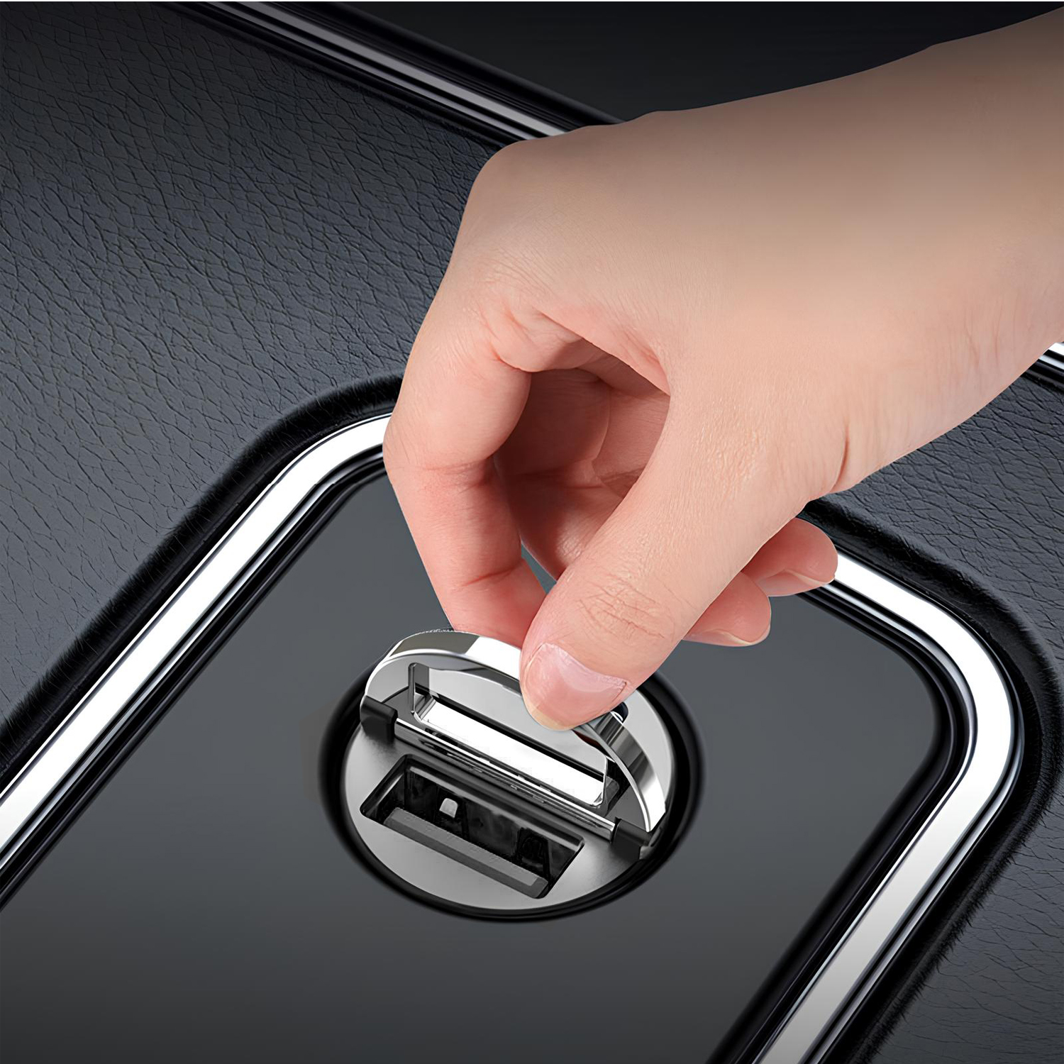 Dłoń wkłada mały, metalowy przedmiot w czarną, błyszczącą powierzchnię. Obiekt otoczony jest srebrną ramą.