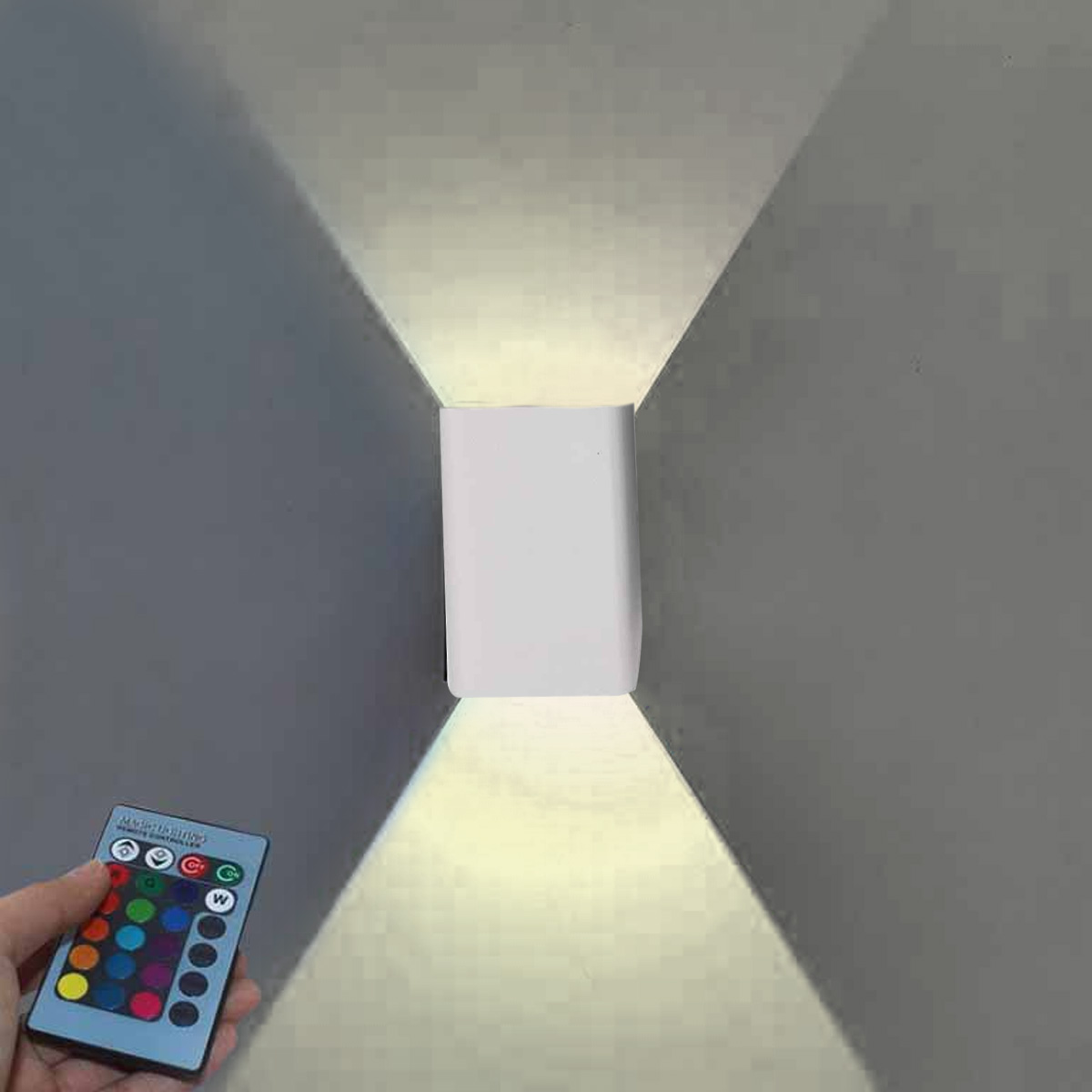 Eine weiße Wandleuchte beleuchtet eine Wand. Eine Hand hält eine Fernbedienung mit bunten Knöpfen. Licht strahlt nach oben und unten.