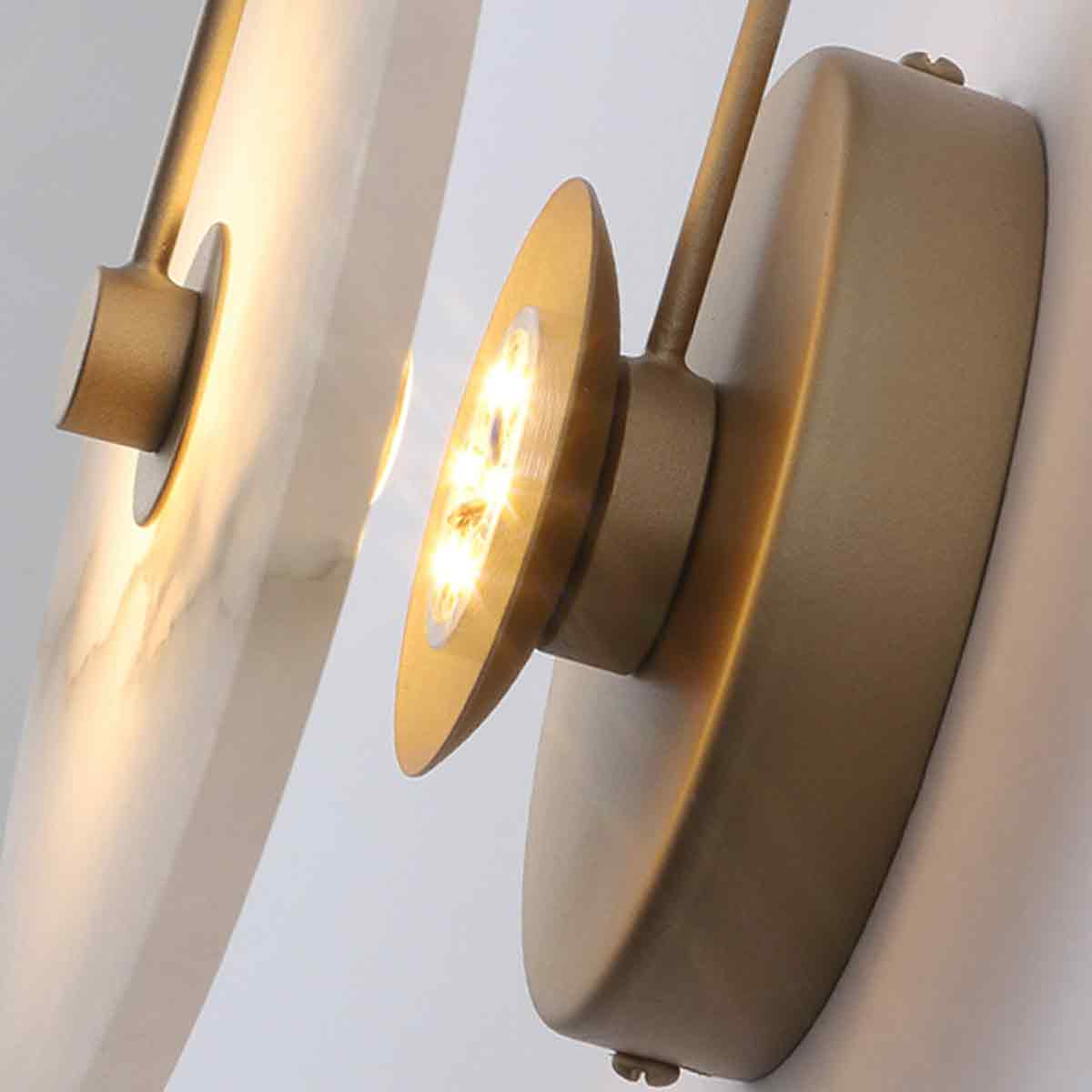 Nahaufnahme von modernen Wandleuchten mit goldenen Armaturen. Eine Leuchte ist eingeschaltet und leuchtet hell. Der Hintergrund ist eine weiße Wand.