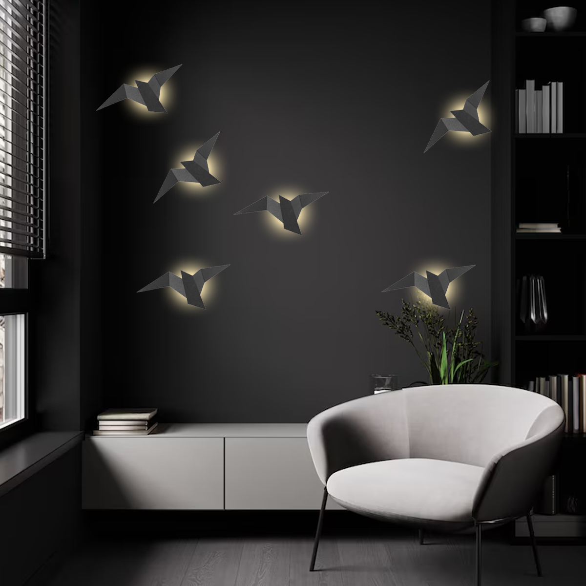 Dunkelgraue Wand mit vogelförmigen Lichtern. Ein weißer Stuhl, Schrank und Bücherregale sind im Raum. Links ein Fenster mit Jalousien.
