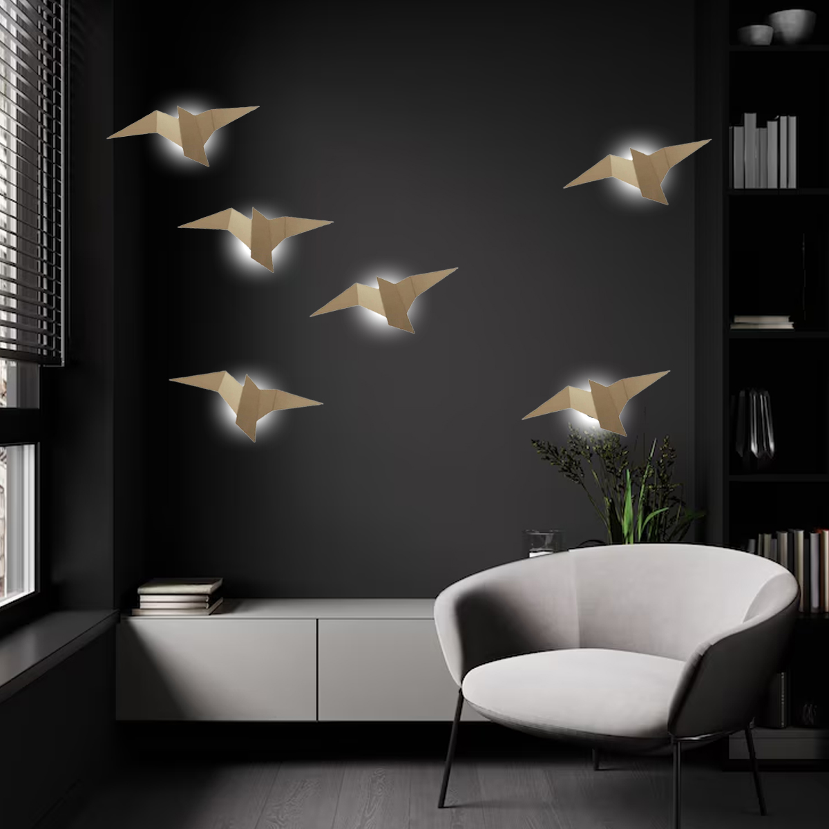 Ein modernes Interieur mit origami-förmigen Vogellichtern an einer dunklen Wand. Ein weißer Stuhl, Schrank und Bücherregal sind ebenfalls zu sehen.