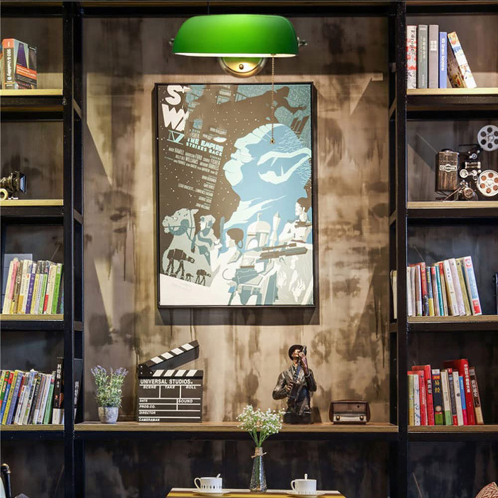 Ein Raum mit Bücherregalen, einem Filmplakat, einer grünen Lampe und filmbezogenen Gegenständen wie einer Klappe und einer Kamerafigur.