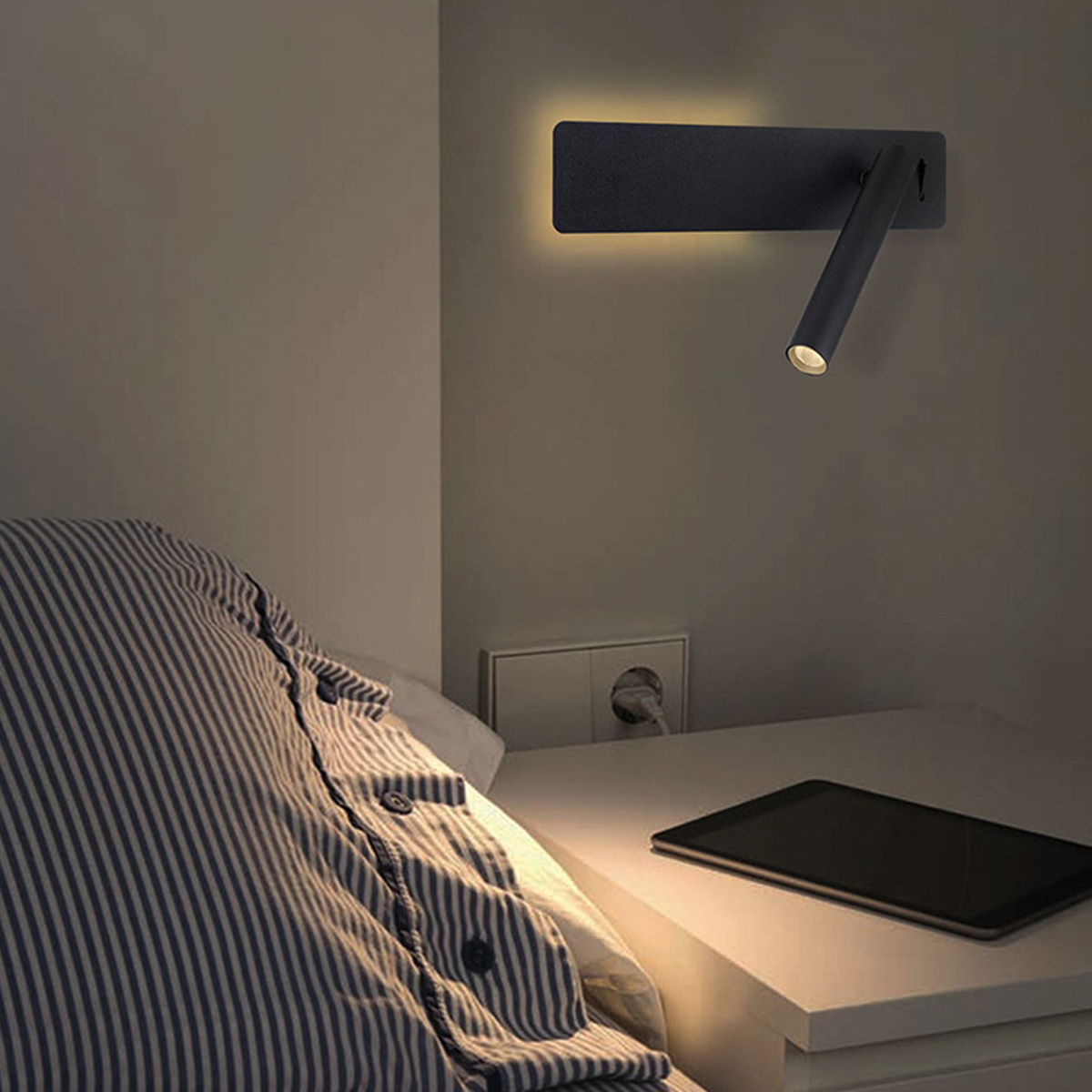 Schlafzimmer mit Wandleselampe. Ein Bett mit gestreiften Laken ist sichtbar. Ein Tablet liegt auf dem Nachttisch.