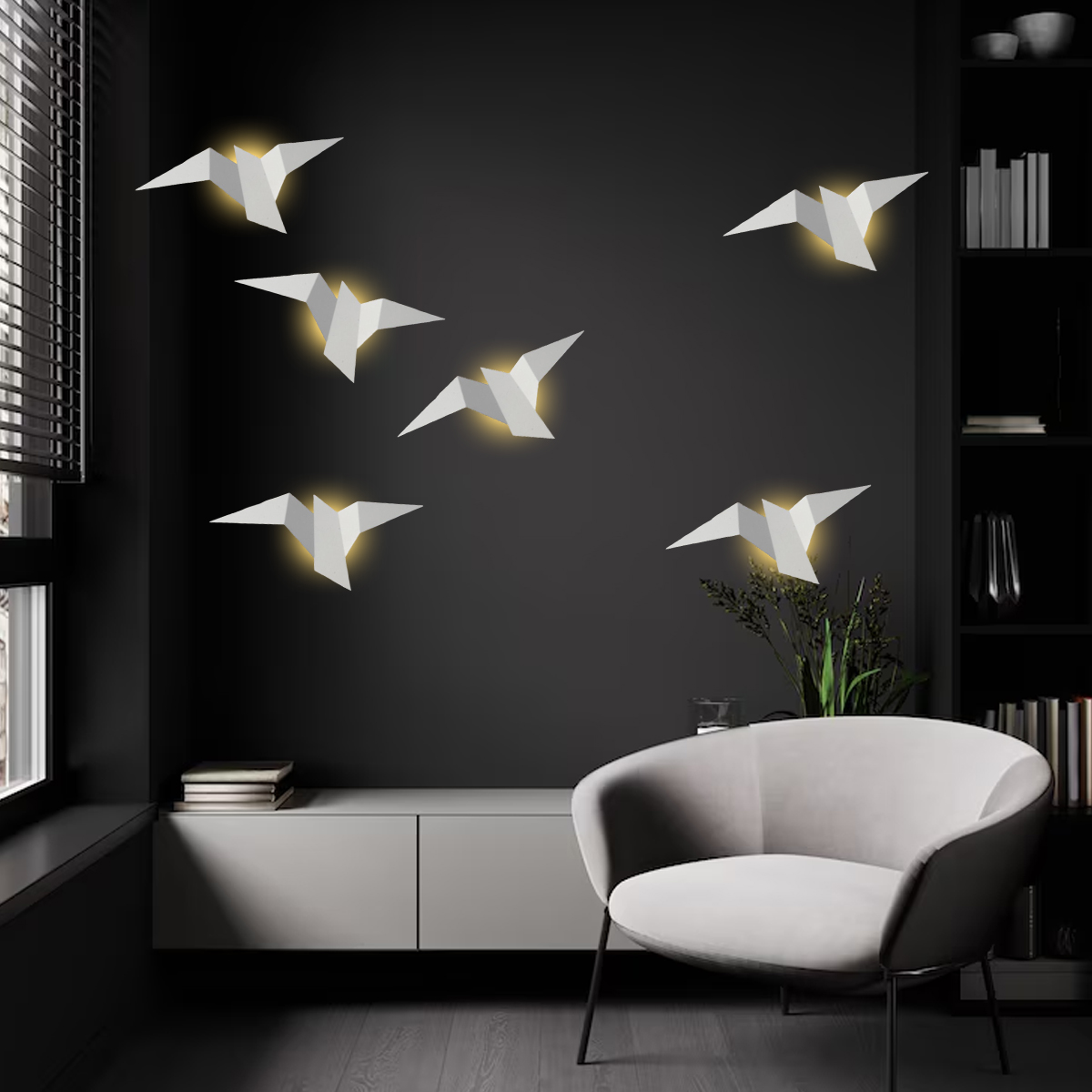 Modernes Wohnzimmer mit Origami-Vogellichtern an einer dunklen Wand. Ein weißer Stuhl, Schrank und Fenster sind ebenfalls vorhanden.