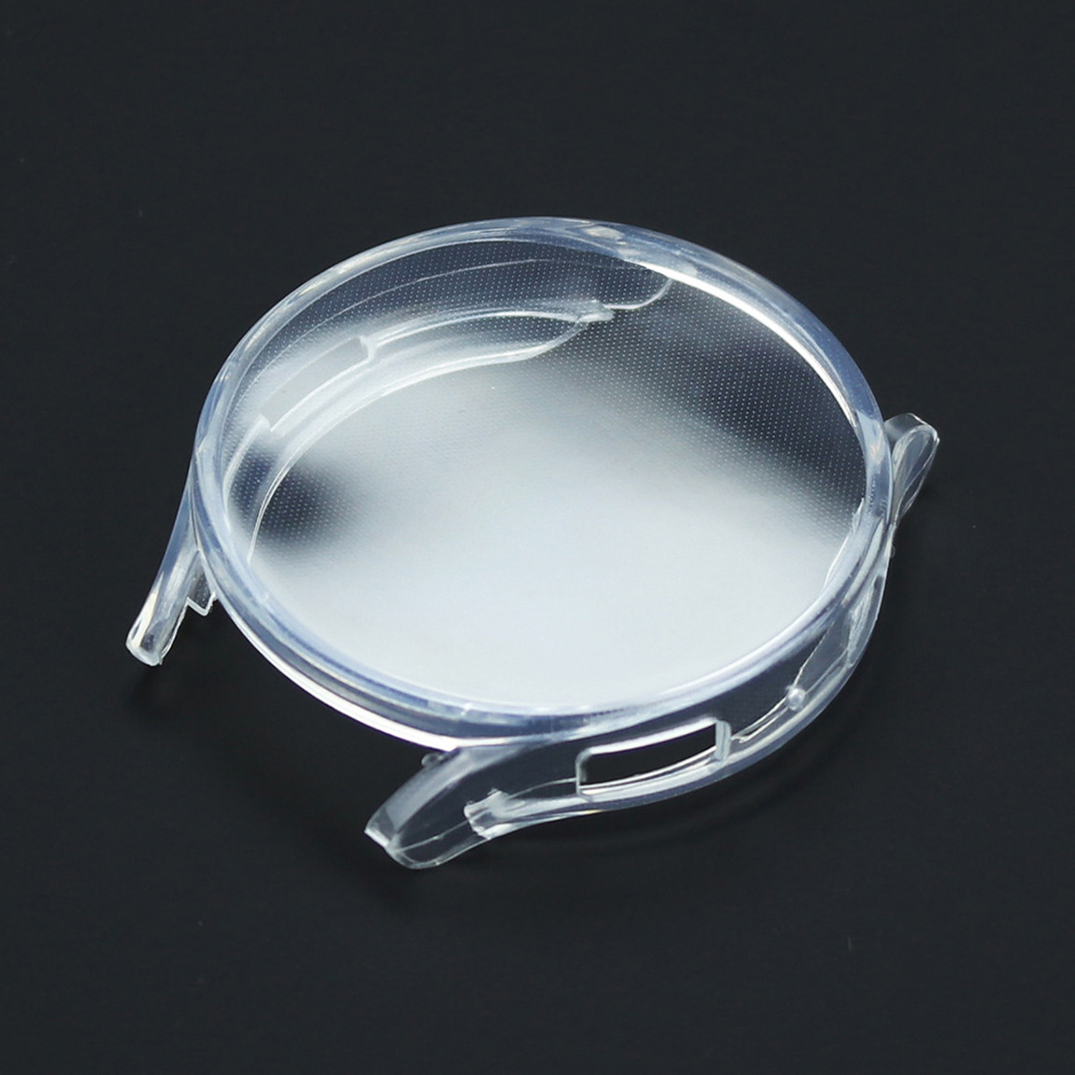 Ein klarer, transparenter Uhrengehäuseschutz liegt auf einer schwarzen Oberfläche. Es hat eine runde Form mit zwei seitlichen Clips.