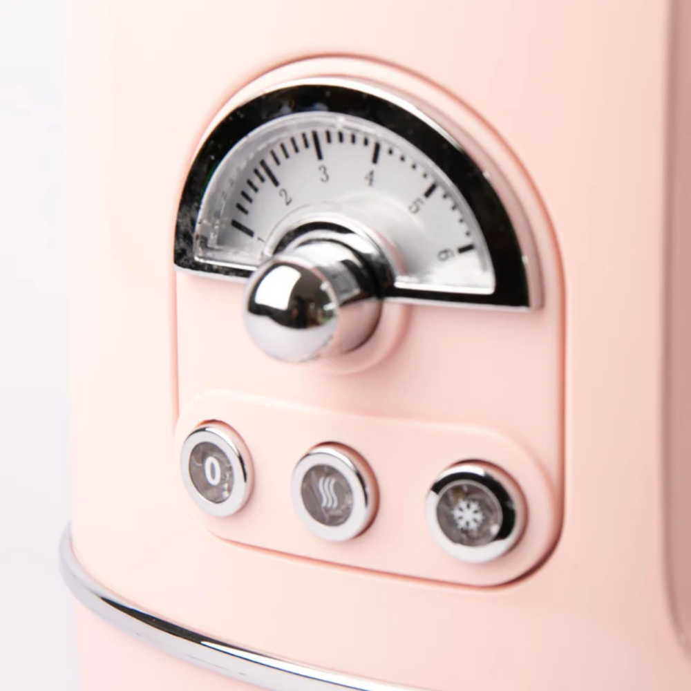 Nahaufnahme eines rosa Geräts mit Chrom-Zifferblatt und Knöpfen. Das Zifferblatt zeigt Einstellungen von 1 bis 6. Knöpfe mit 0, Dampf und Schneeflocken.