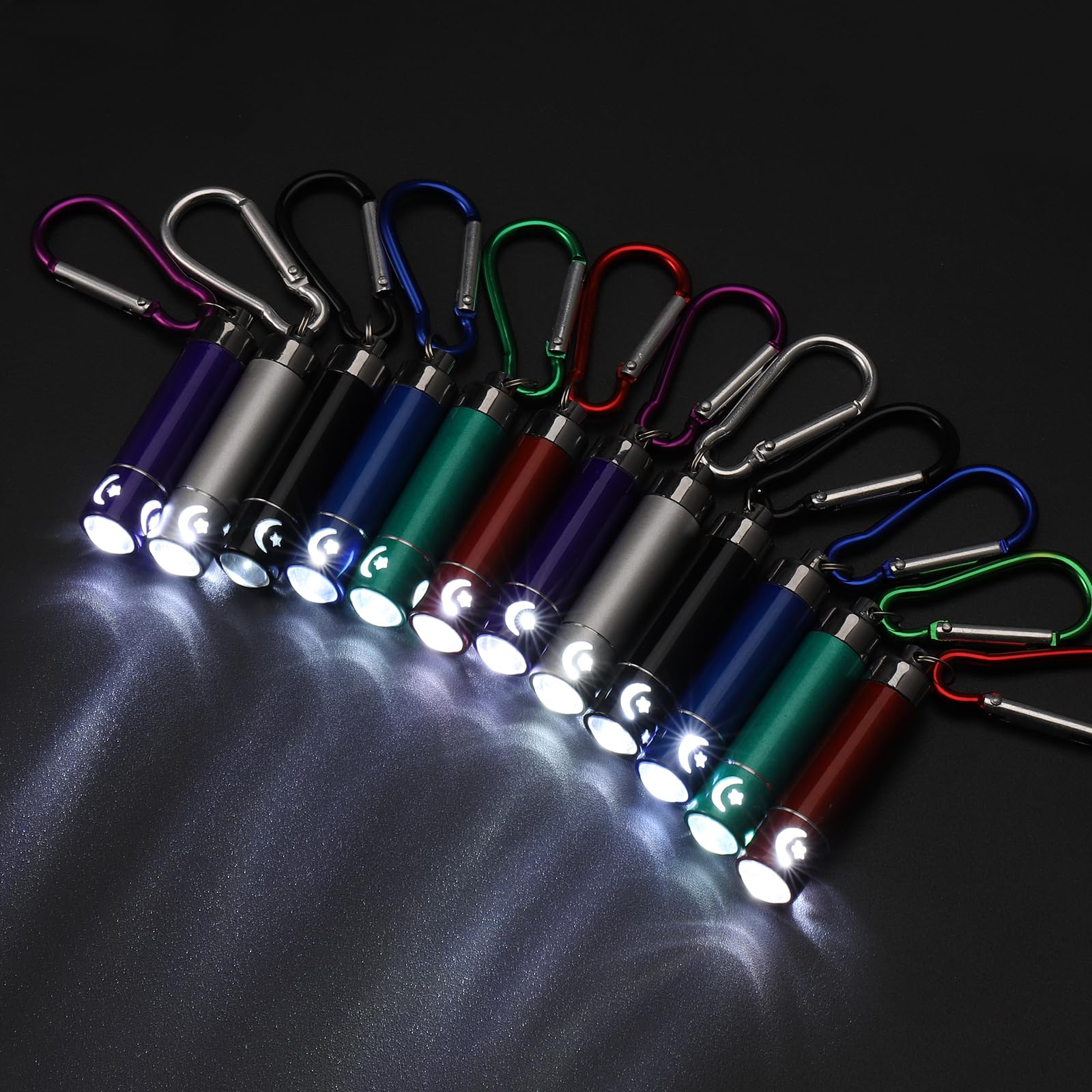 Reihe bunter Taschenlampen mit Karabinern, die Licht auf eine dunkle Oberfläche scheinen. Jede Taschenlampe hat ein Mond- und Stern-Design.