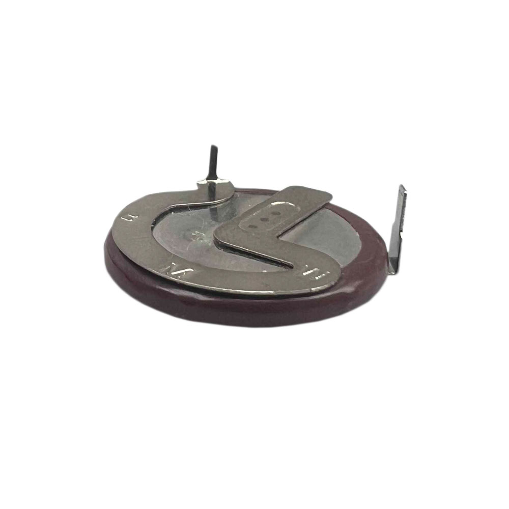 Zbliżenie małego, okrągłego elementu elektronicznego. Ma bordową podstawę, srebrne metalowe części i czarny bolec wystający do góry.