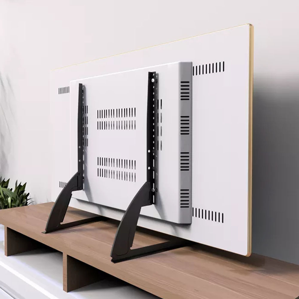 Biały telewizor zamontowany na drewnianym stole. Czarne metalowe wsporniki trzymają telewizor. Ściana za nim jest biało-szara.