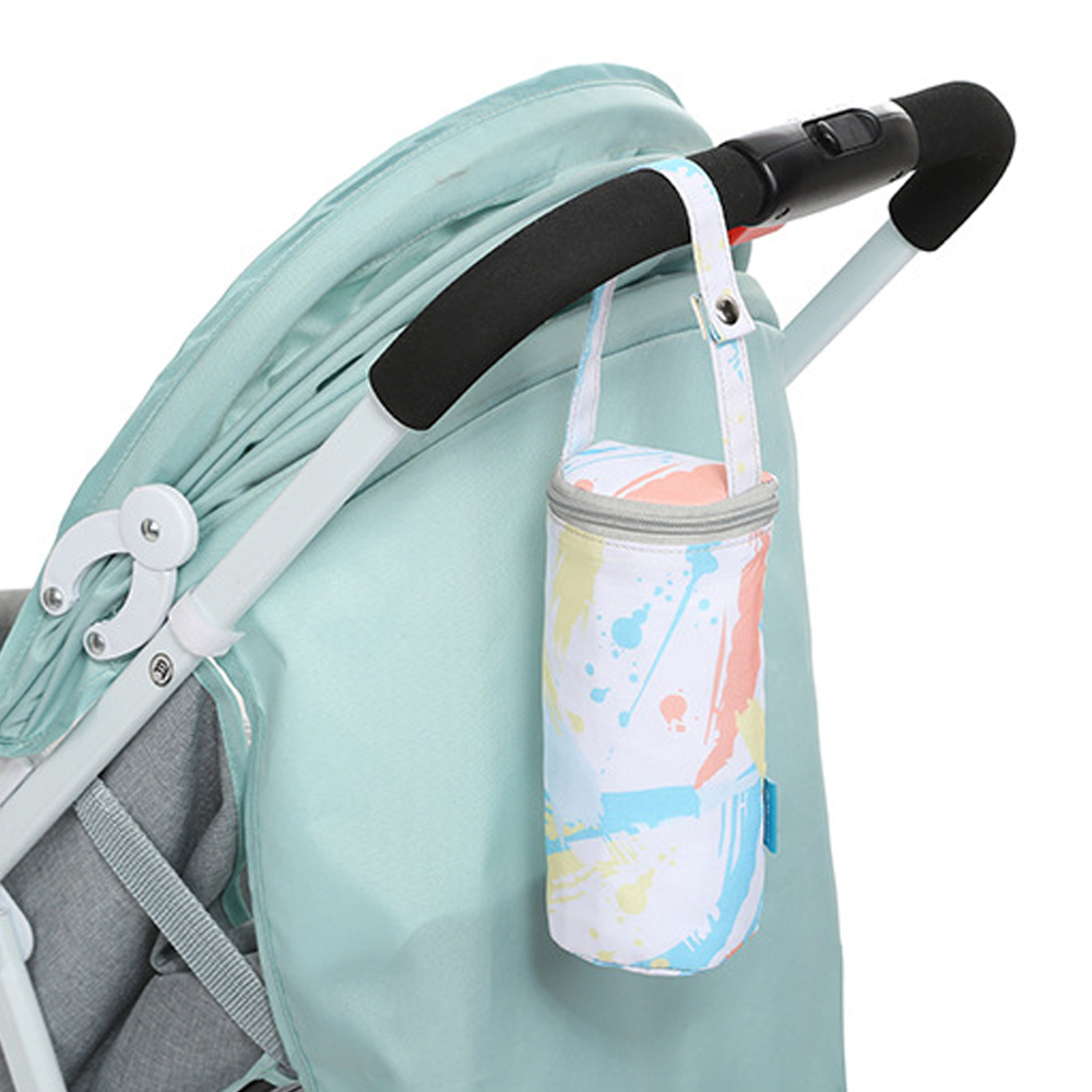 Eine Babyflaschentasche mit bunten Farbspritzern hängt an einem Kinderwagengriff. Der Kinderwagen hat ein mintgrünes Verdeck.
