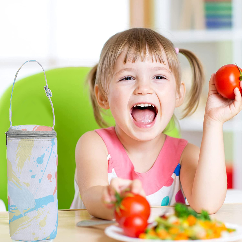 Ein lachendes Mädchen hält Tomaten. Links eine Babyflaschentasche. Gemüse auf einem Teller. Grüner Stuhl im Hintergrund.