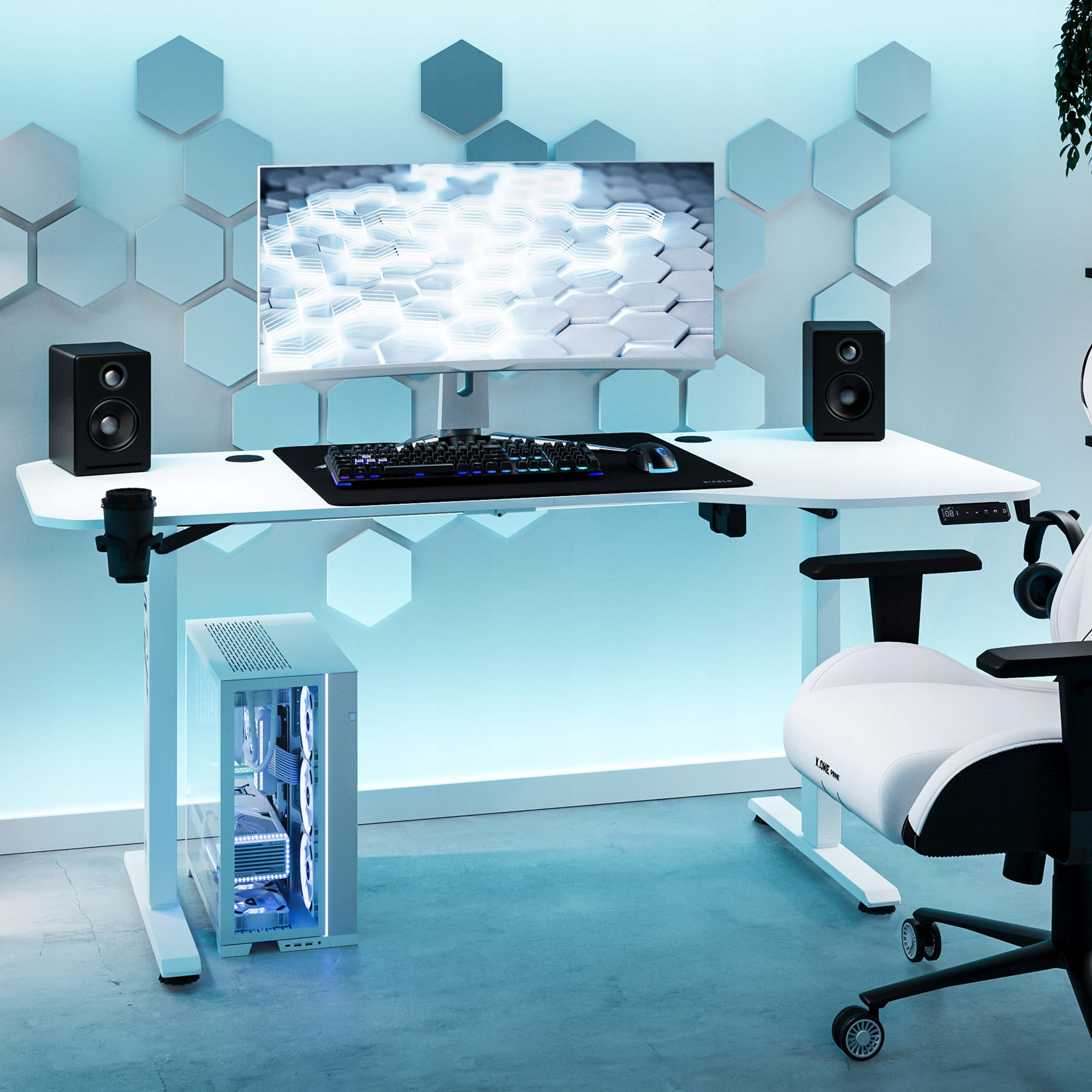 Białe biurko gamingowe z monitorem, głośnikami, klawiaturą i komputerem. Obok biało-czarny fotel.