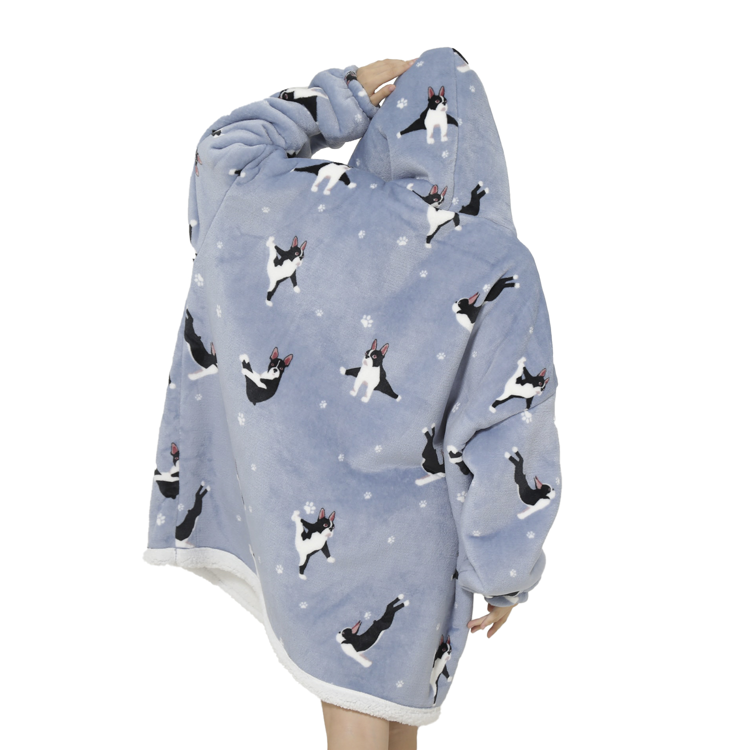 Una persona lleva una manta con capucha azul con estampados de perros blancos y negros. La manta tiene un ribete blanco.