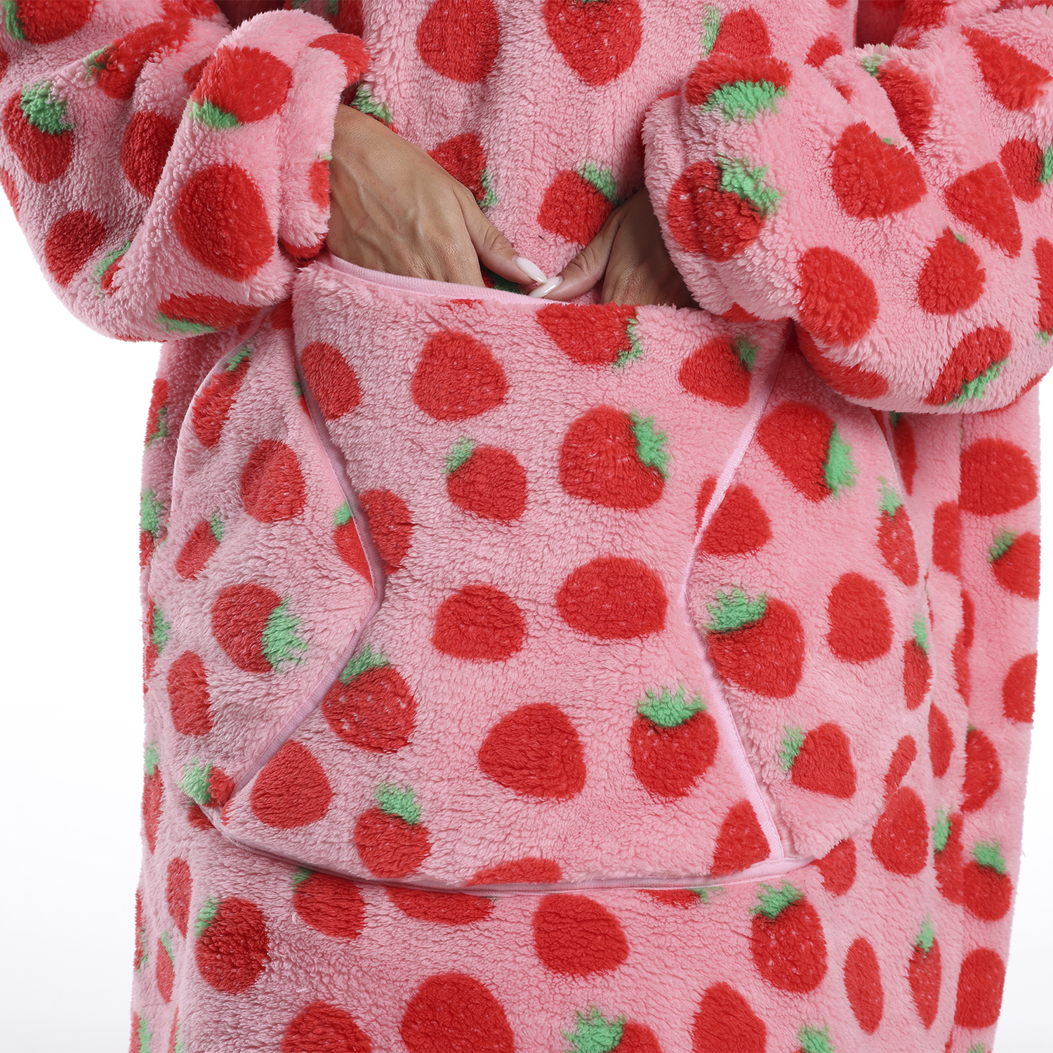 Una persona indossa una coperta in pile rosa a fantasia fragole. Le mani sono dentro la tasca anteriore. Fragole rosse con cime verdi.