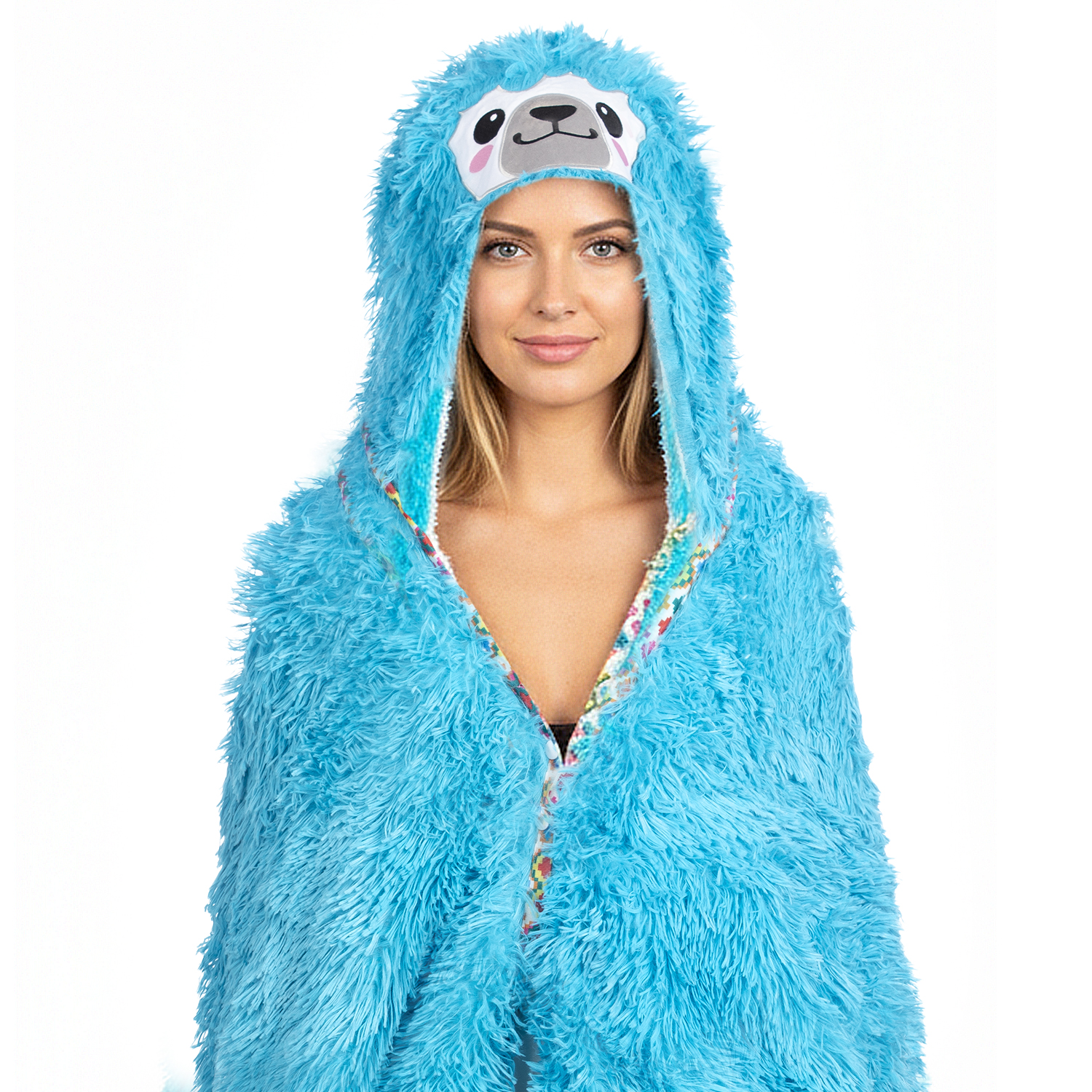 Una donna indossa una coperta con cappuccio a forma di bradipo blu. Il cappuccio ha la faccia di un bradipo. Sorride e lo sfondo è bianco.