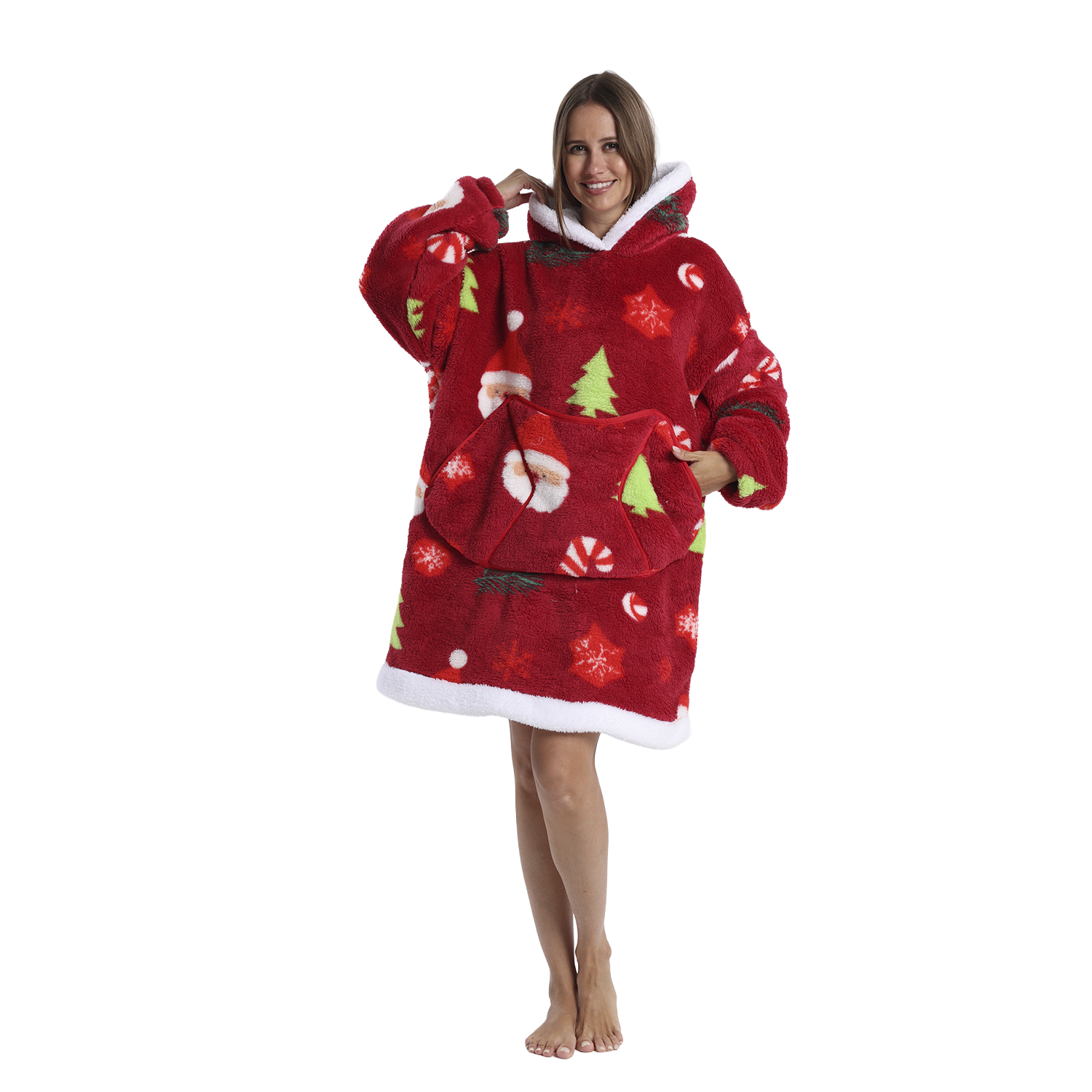 Una donna con una felpa natalizia rossa con motivi di Babbo Natale e alberi, finiture bianche e cappuccio. Sorride ed è a piedi nudi.