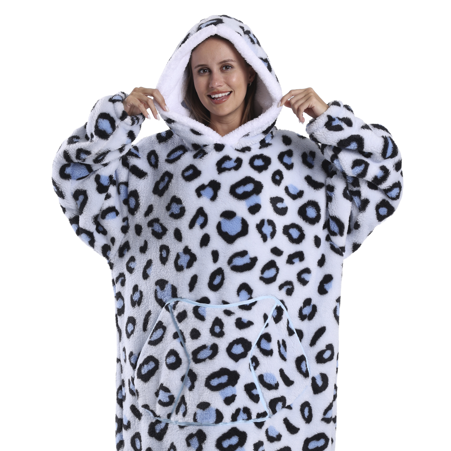 Una donna sorride, indossa una coperta con cappuccio con stampa leopardata bianca, blu e nera. Tiene i bordi del cappuccio.