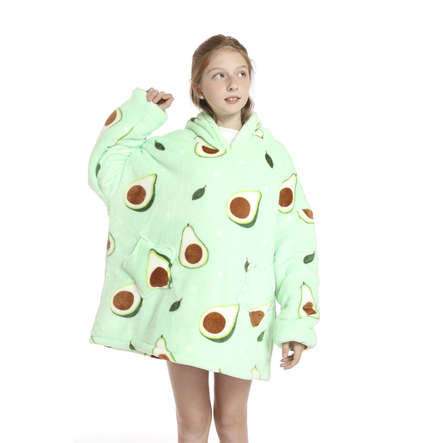 Una niña con una sudadera con capucha con estampado de aguacate. La sudadera es verde claro y tiene diseños de aguacate y hojas. Está sobre fondo blanco.