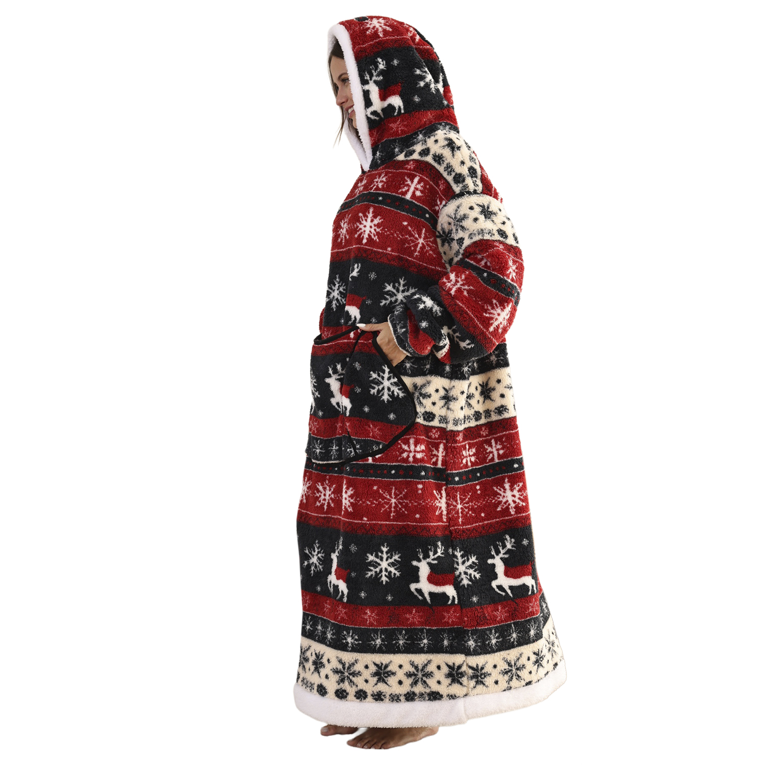 Una mujer de pie con una bata con capucha larga con un diseño navideño. La bata es roja, negra y crema, con renos y copos de nieve.