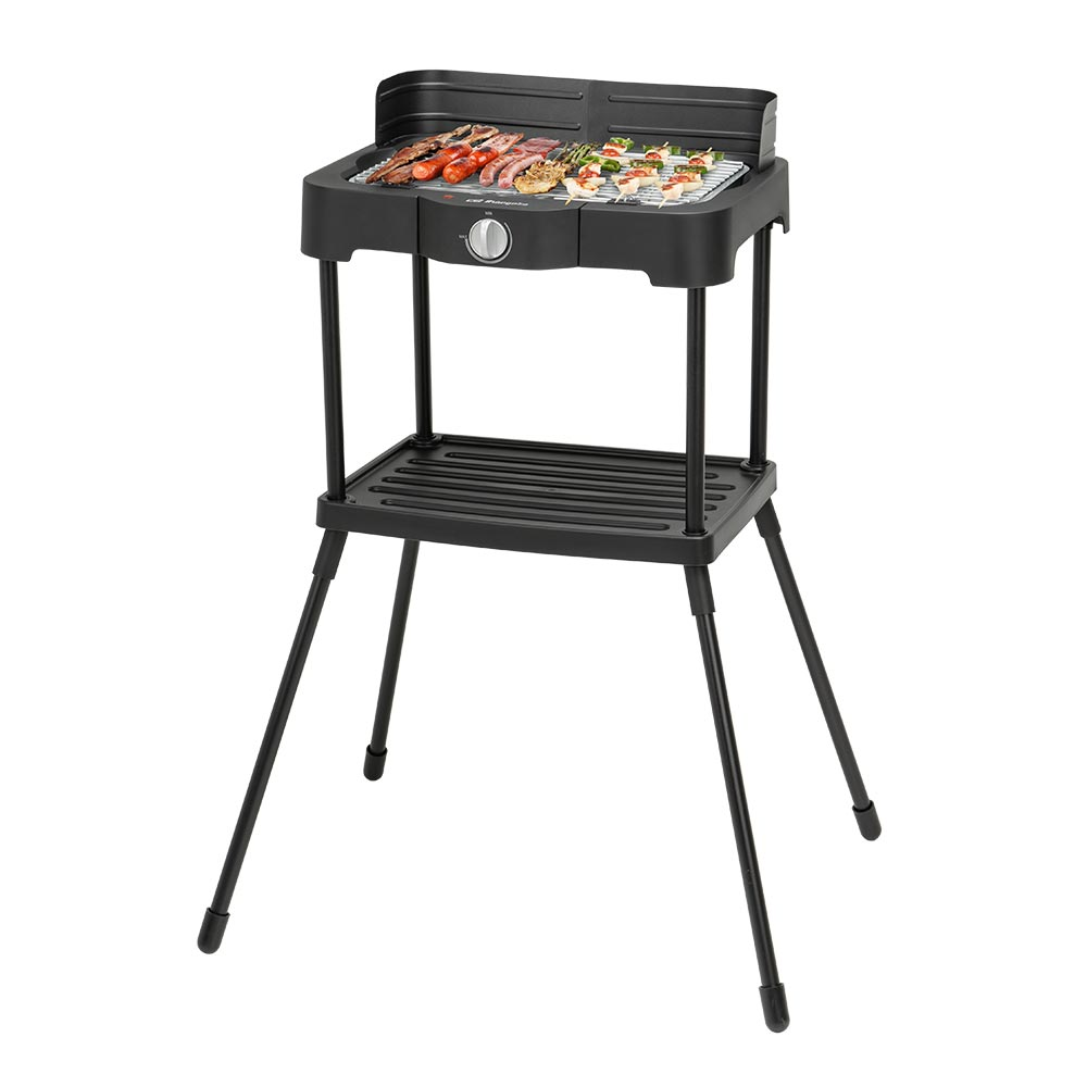 Parrilla eléctrica negra con comida encima, incluyendo salchichas y verduras. Tiene un estante inferior y cuatro patas.
