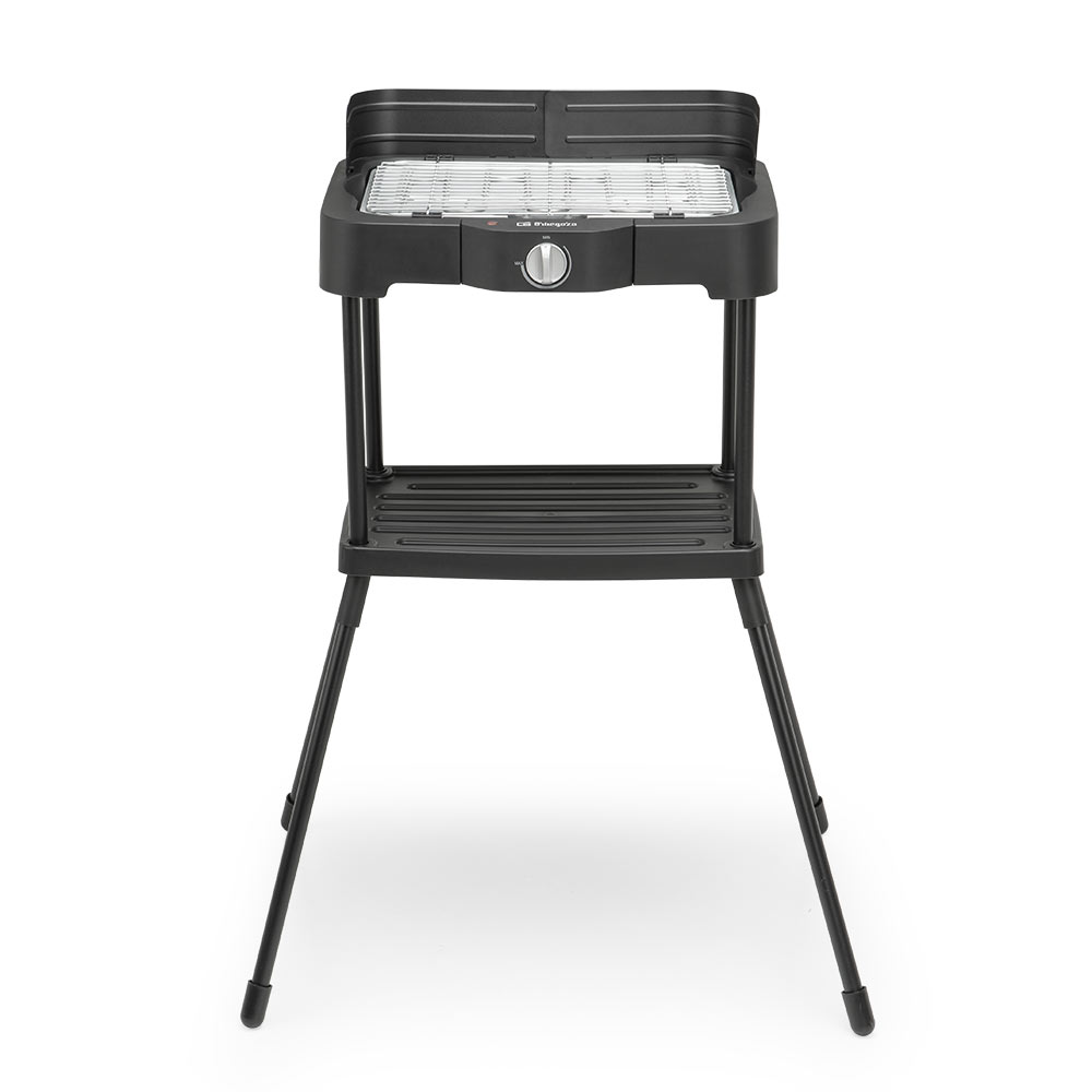 Una parrilla eléctrica negra sobre un soporte. Tiene una superficie para asar, una perilla de control y una repisa inferior. El soporte tiene cuatro patas.