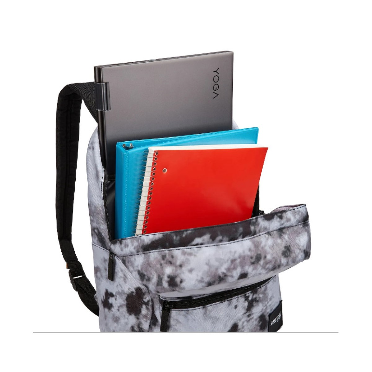 Ein Rucksack mit Laptop, blauem Ordner und rotem Notizbuch. Der Rucksack hat ein Batikmuster.