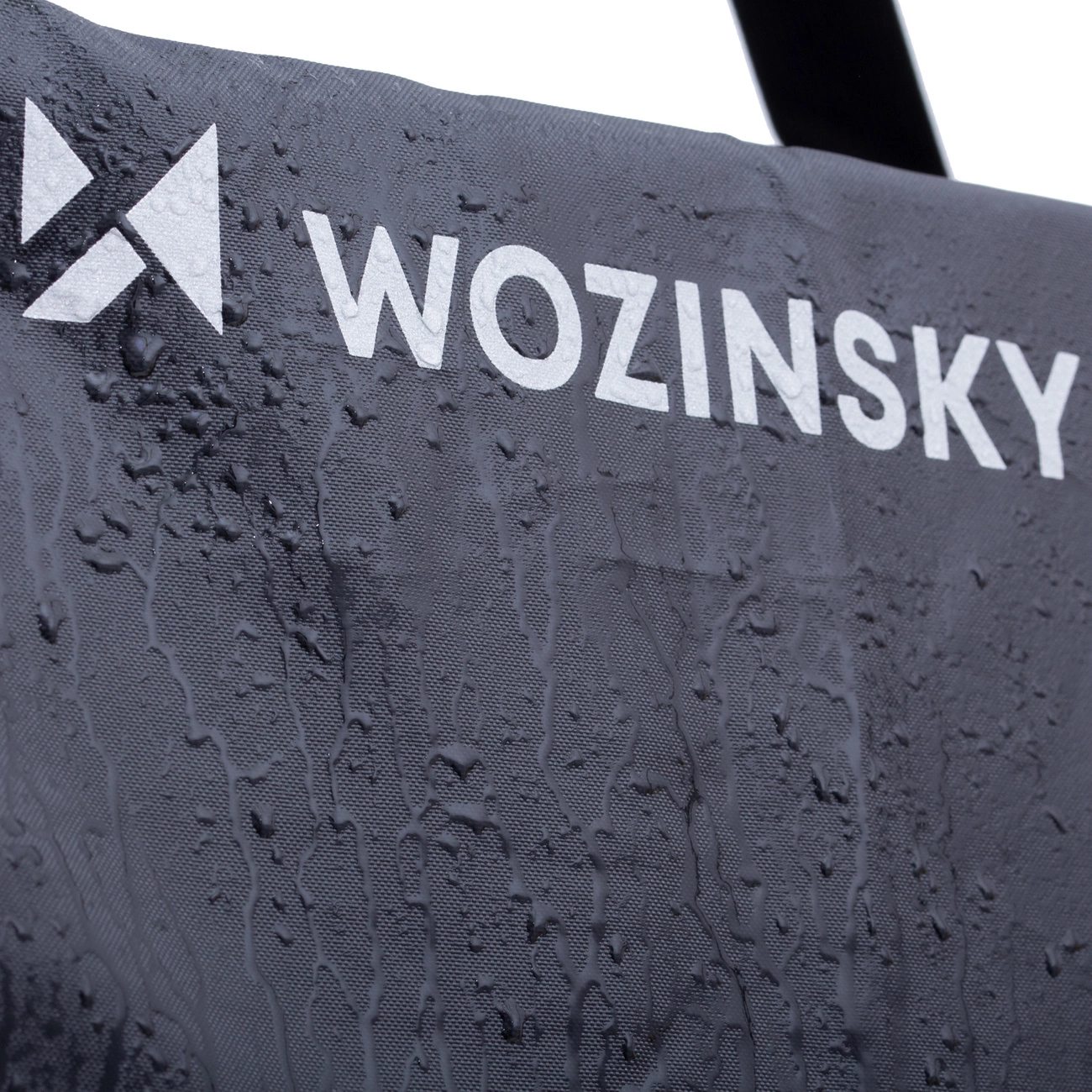 Nahaufnahme einer dunklen, strukturierten Oberfläche mit dem weißen Schriftzug 'WOZINSKY'. Wassertropfen sind sichtbar.