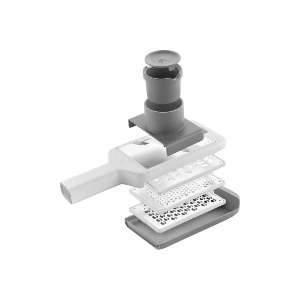 Widok z rozłożeniem białej i szarej tarki kuchennej, z wieloma płytkami do tarcia i pojemnikiem na górze.