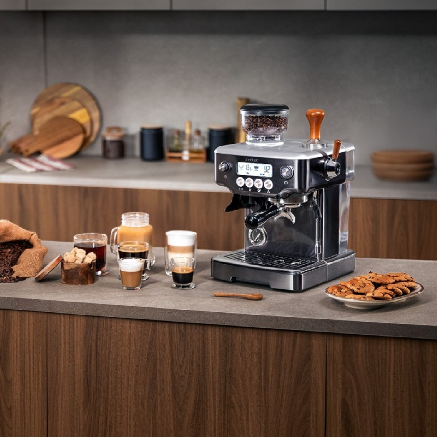 Macchina da caffè con chicchi di caffè, varie bevande al caffè in bicchieri e biscotti su un piano cucina.