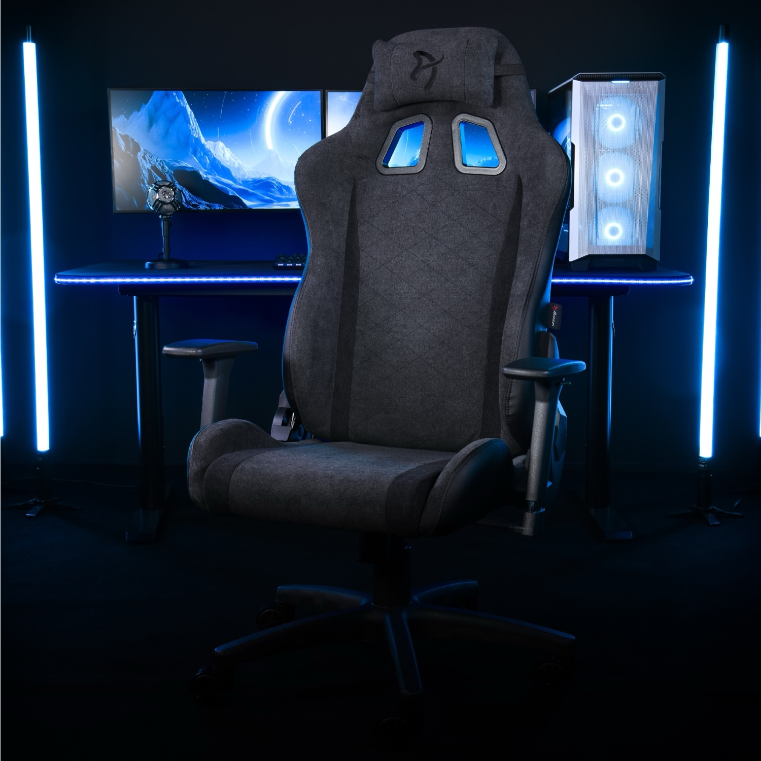 Sedia da gaming davanti a una scrivania con PC e monitor. Luci blu illuminano la scena, creando un'estetica moderna.